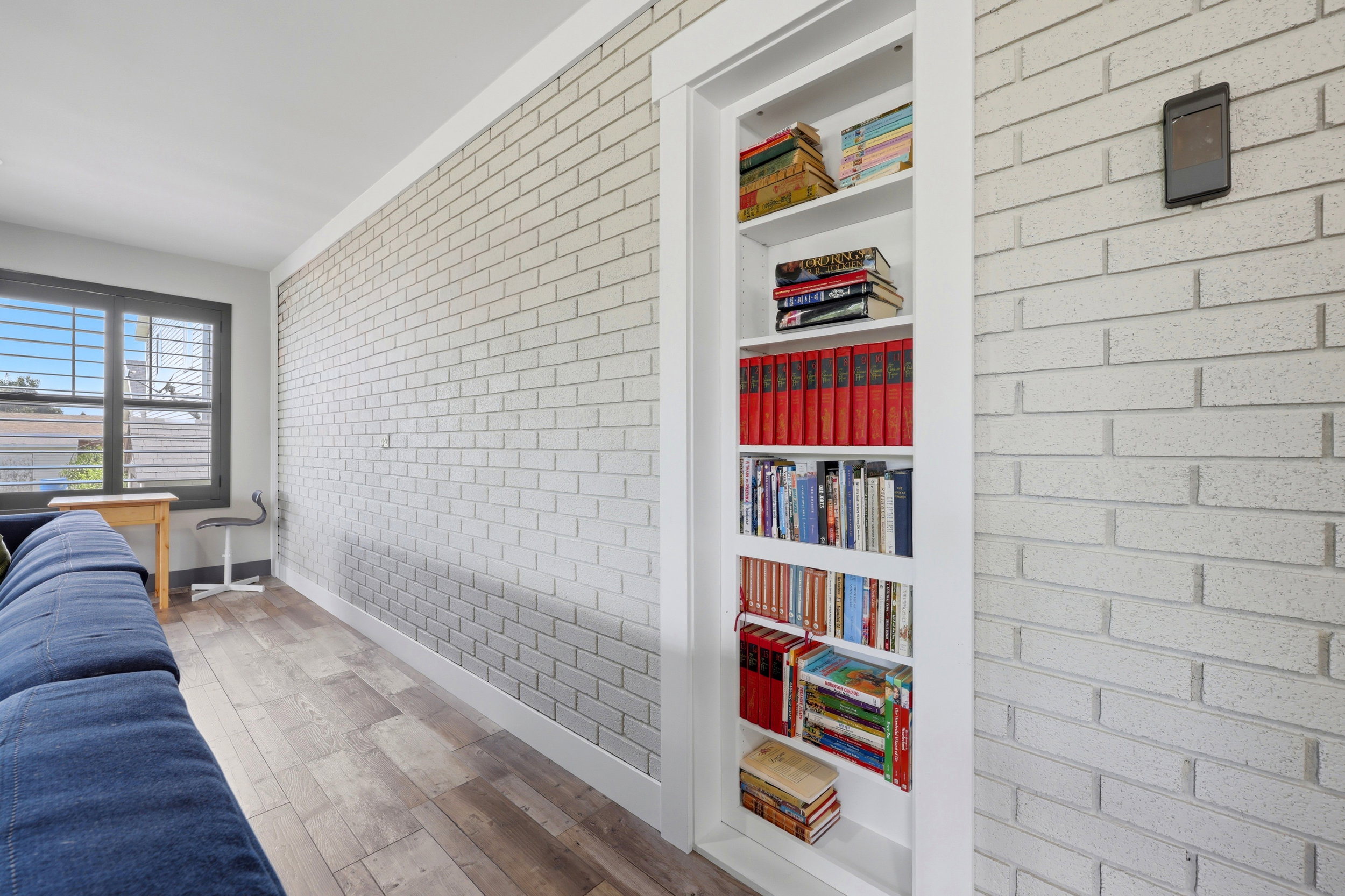 Built-in shelving with white trim and a concealed door, complemented by light-toned brick-patterned walls