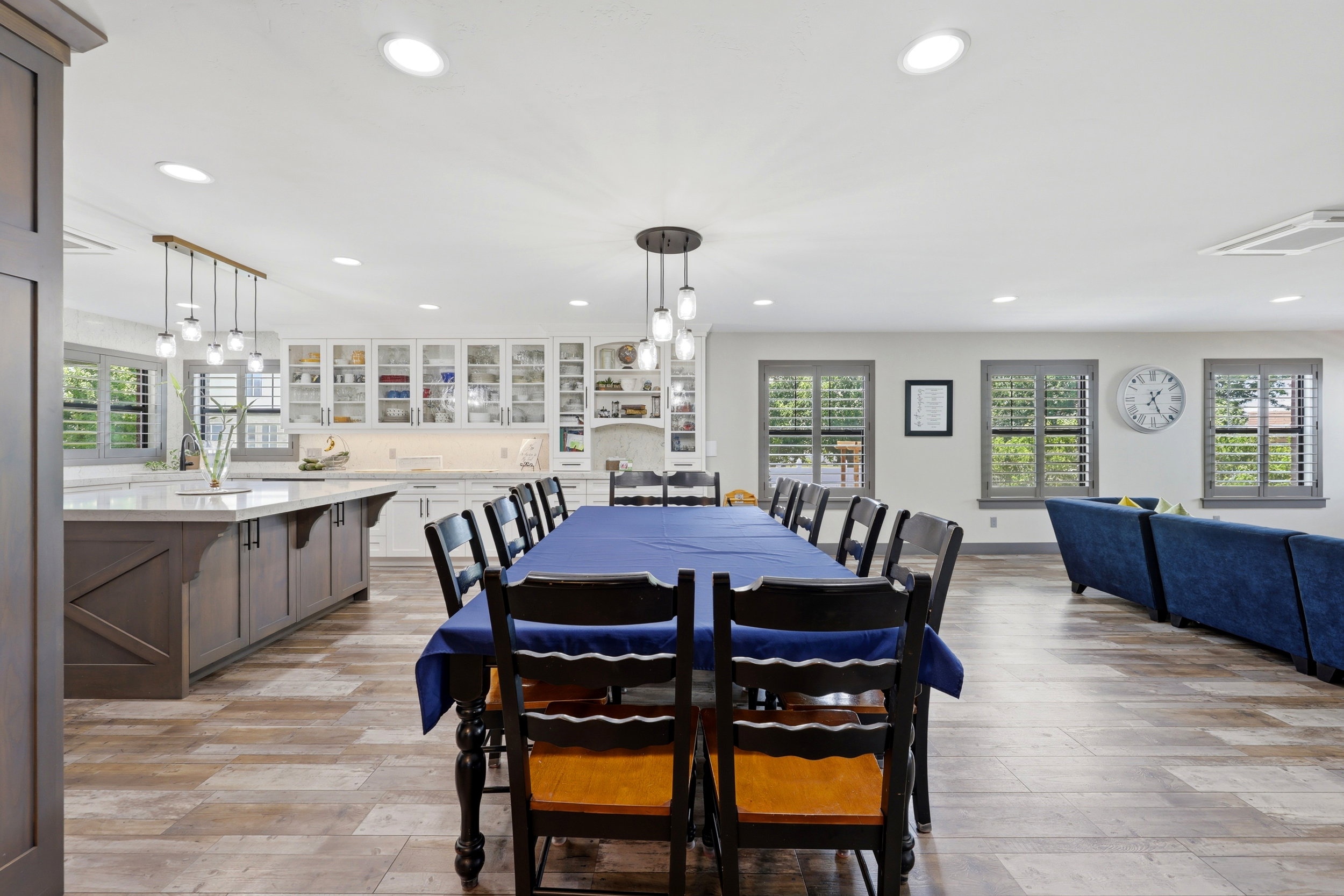 Open-concept kitchen and dining area featuring wood-finish flooring, recessed lighting, and multiple windows with plantation shutters