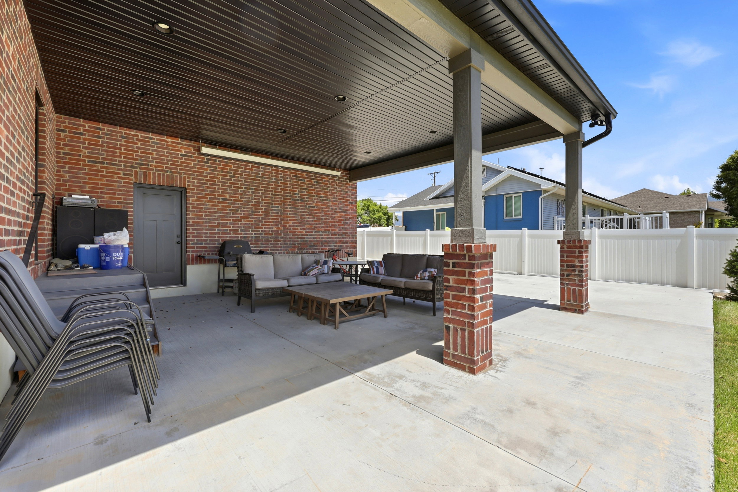 Expansive covered patio featuring brick columns, a flat-panel ceiling with recessed lighting, and a durable concrete surface