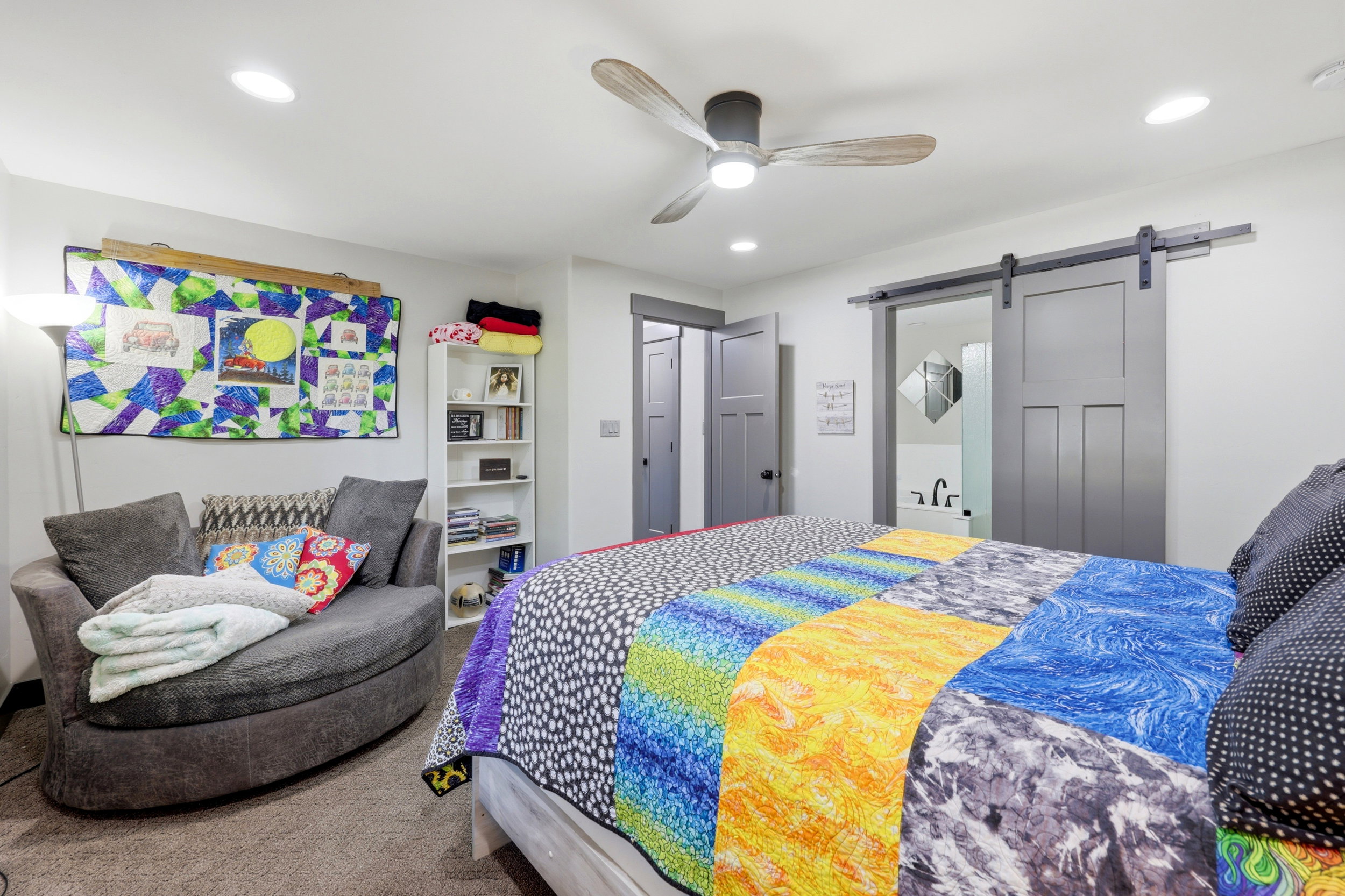 Bedroom featuring a ceiling fan with wood-finish blades, recessed lighting, and a modern barn door leading to an en-suite bathroom