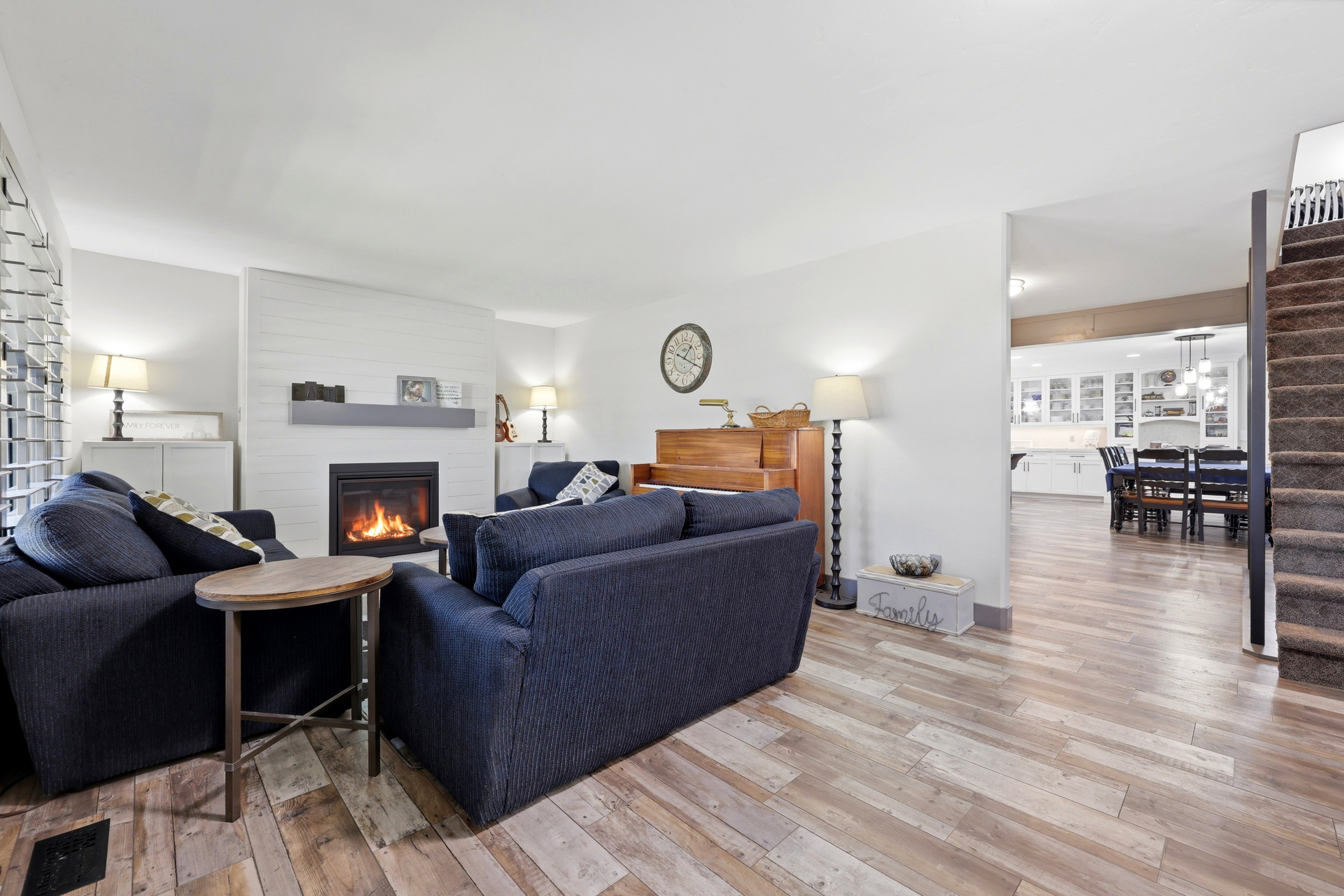 Living space with wood-finish flooring and a fireplace featuring a shiplap-style accent wall and a gray mantel