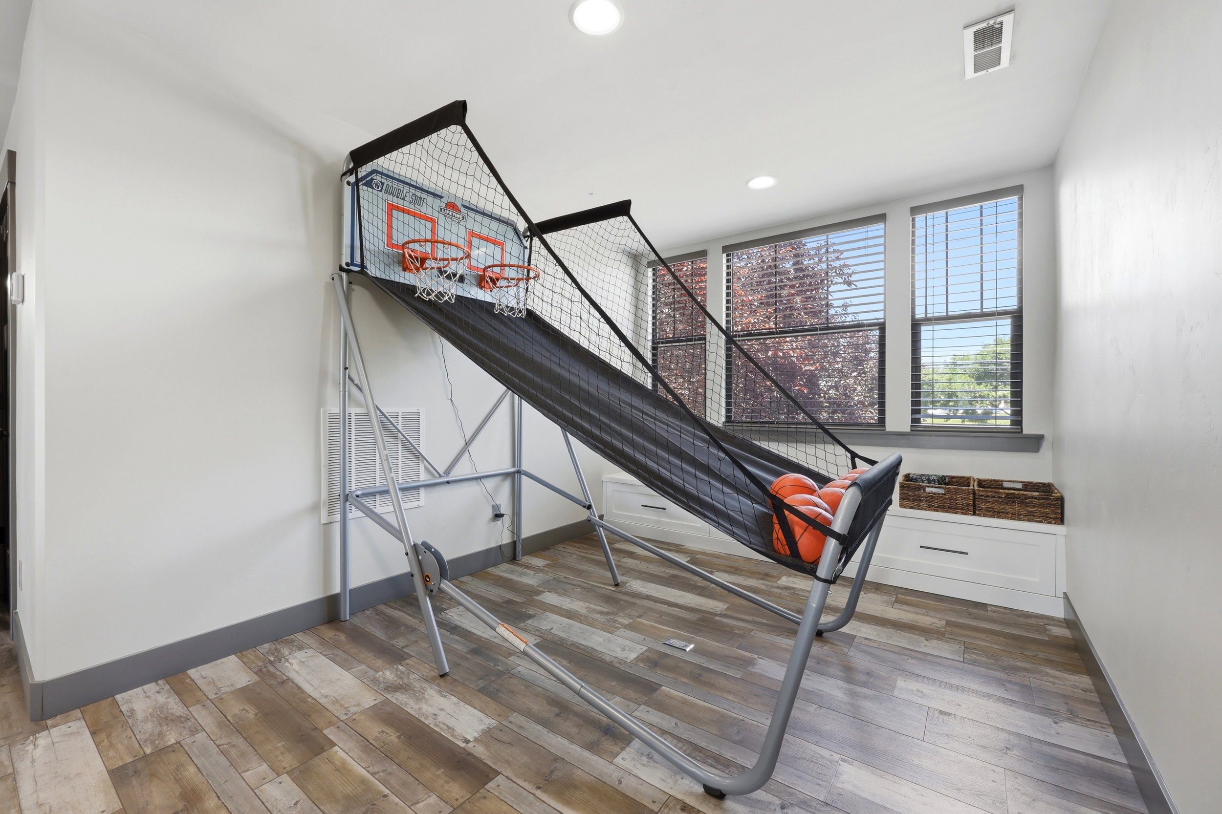 Spacious room featuring wood-finish flooring, white walls, and recessed lighting