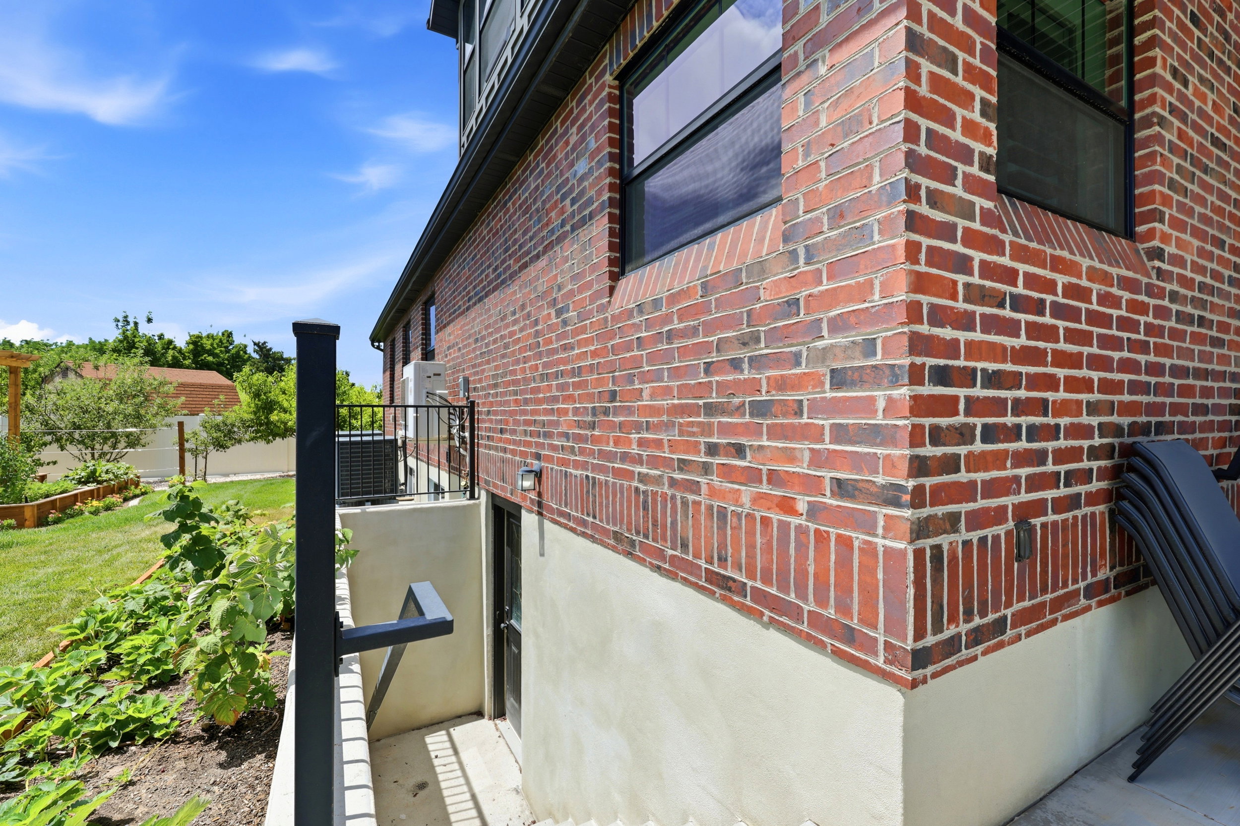 Brick exterior with a light-colored foundation, featuring black-framed windows and a dedicated entry point