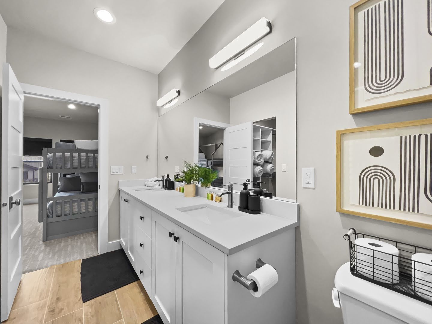 Double vanity featuring white cabinetry, undermount sinks, and a large mirror with integrated lighting