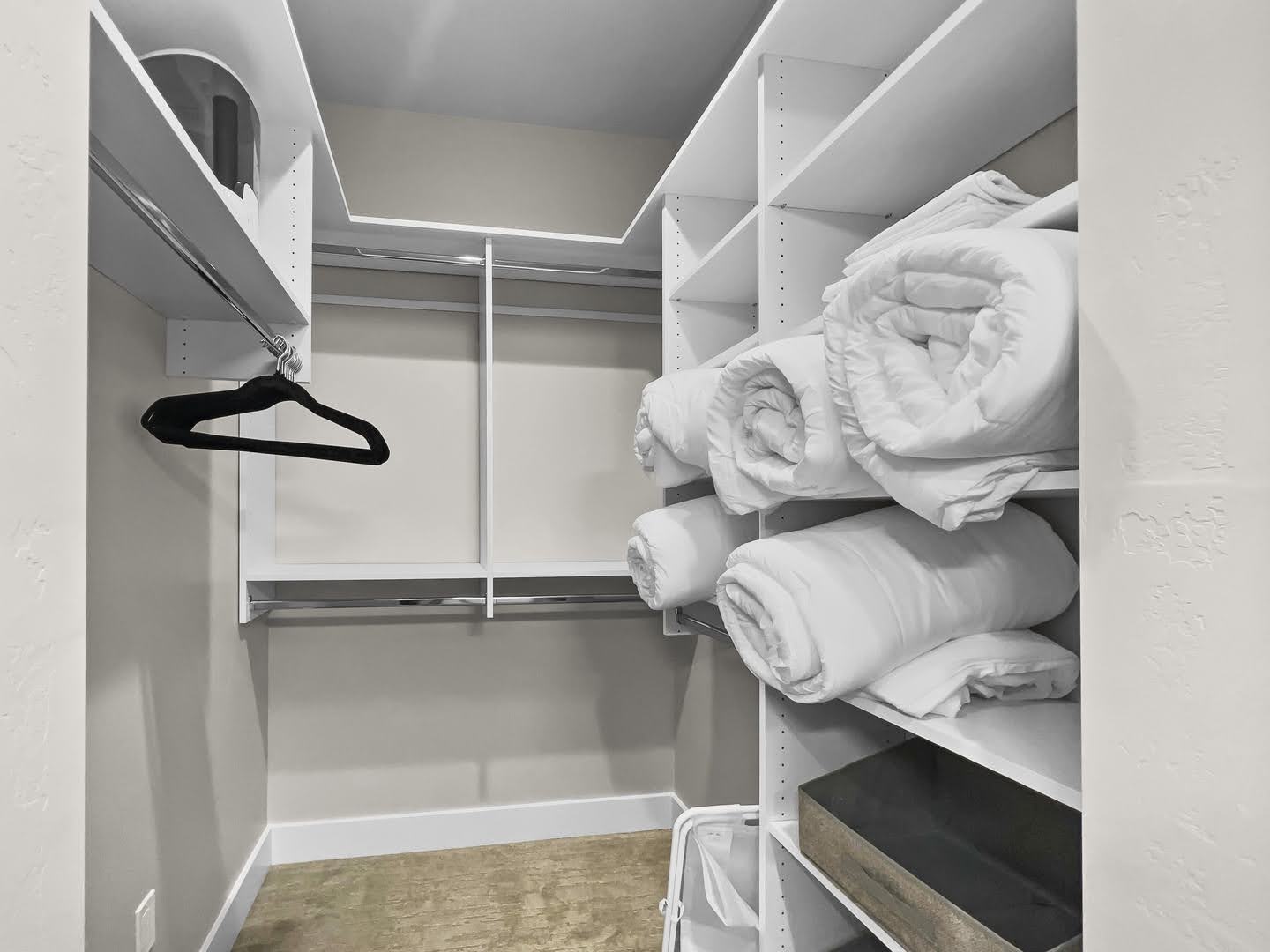 Walk-in closet featuring white built-in shelving, multiple hanging rods, and light-toned wall paint