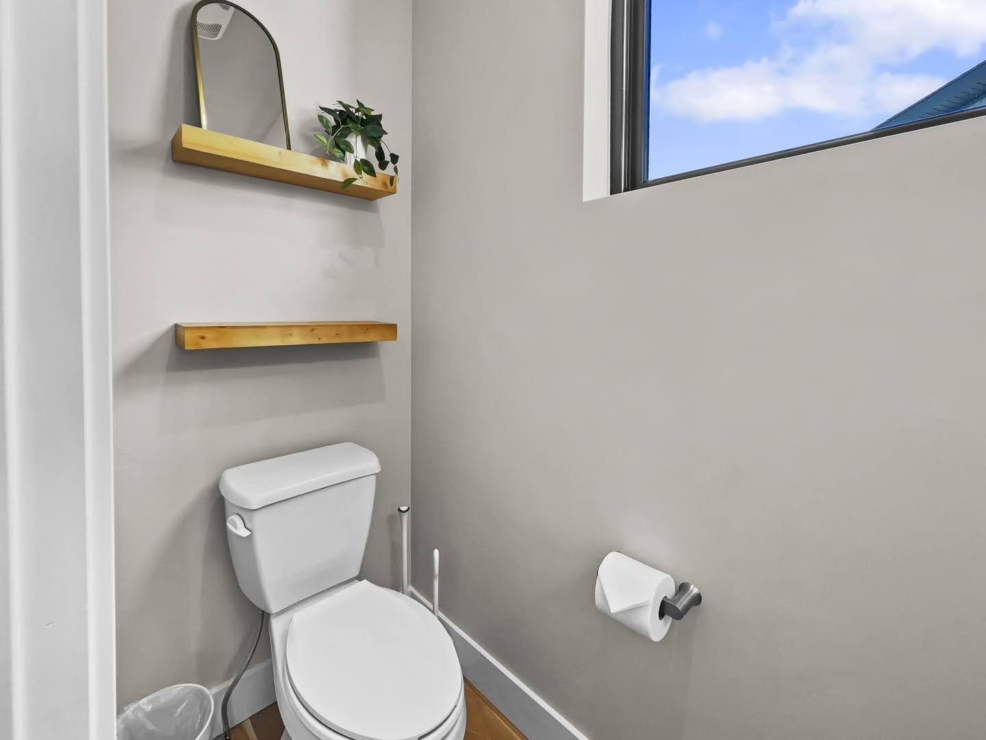 Powder room with a white toilet, light gray walls, and a high window