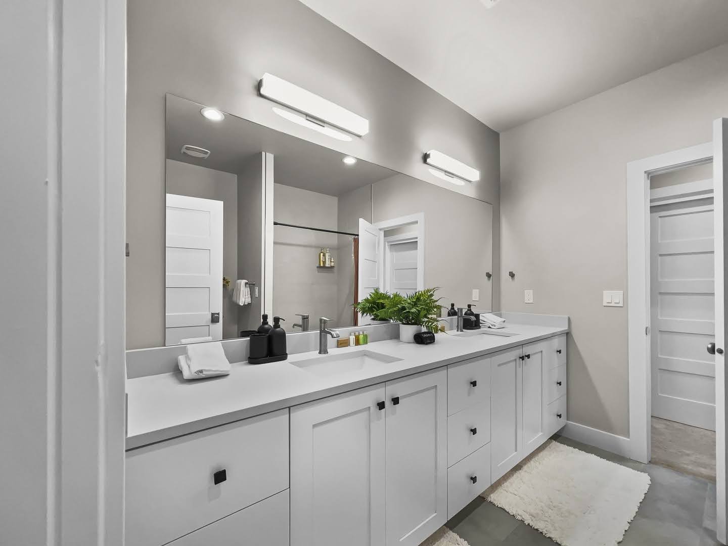 Expansive bathroom featuring a double vanity with ample counter space, dual sinks with chrome faucets, and extensive under-cabinet storage