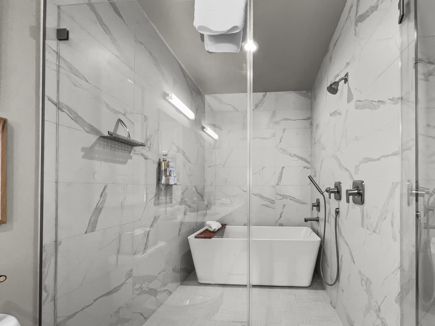 Walk-in shower enclosure featuring a freestanding soaking tub, full-height tile walls, a rain shower head, and a hand-held shower fixture