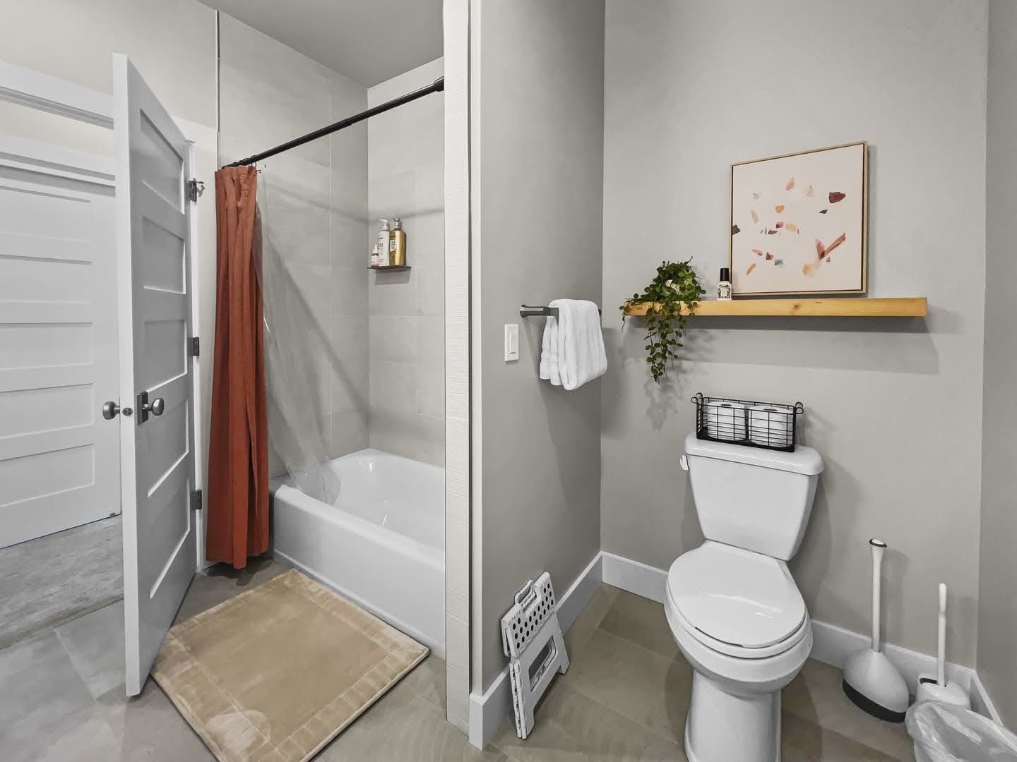 Bathroom featuring a white tub with light gray tile surround, a white toilet, and light gray wall paint