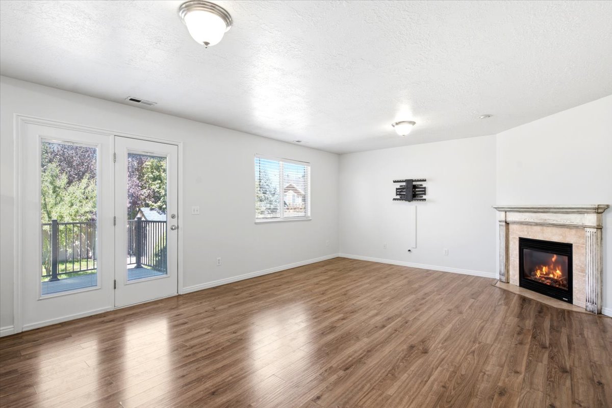 Spacious interior featuring wood-finish flooring, a corner fireplace with a decorative mantel, and white walls