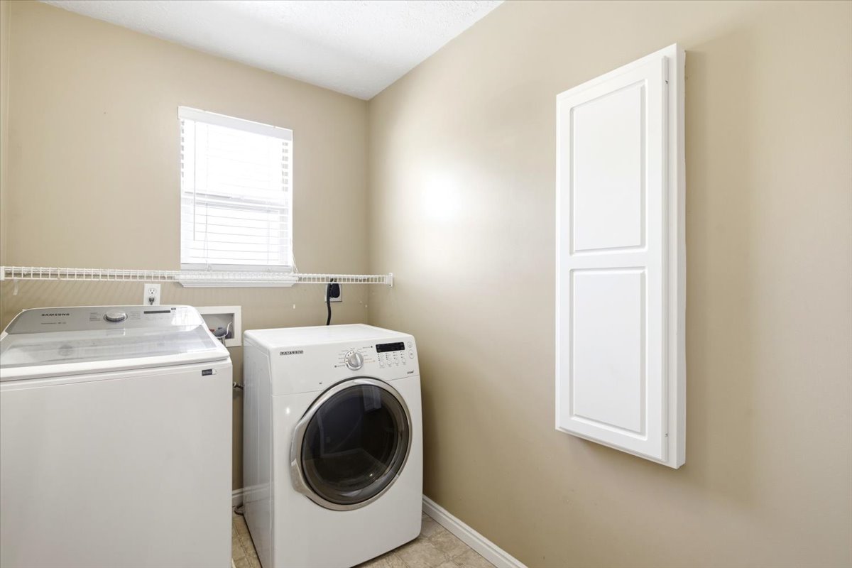 Dedicated laundry area with a window, wall-mounted wire shelving, and neutral wall paint