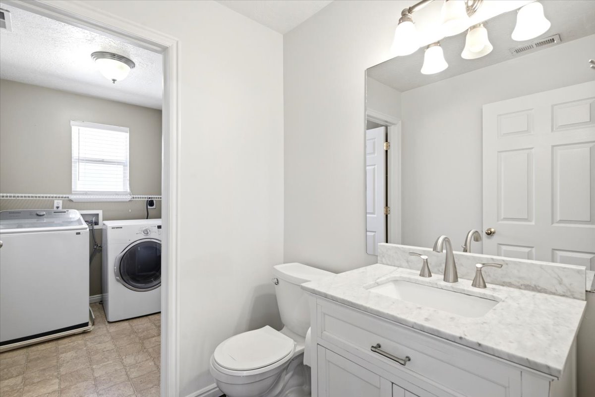 Bathroom vanity with white cabinetry, light-toned countertop, and brushed nickel hardware