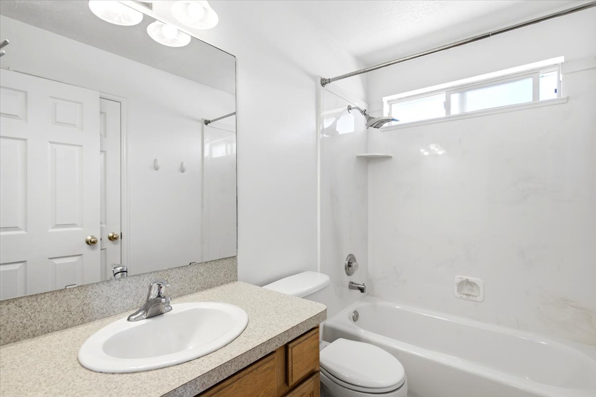Bathroom featuring a wood-finish vanity with an integrated sink and a speckled countertop