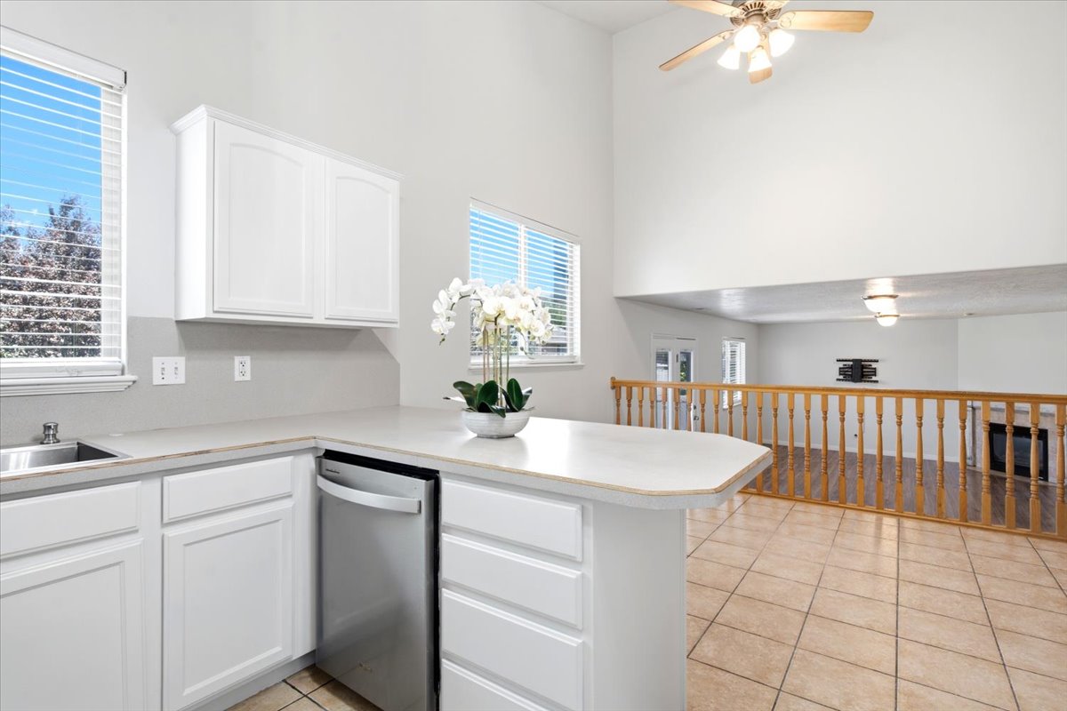 Kitchen with white cabinetry, light-toned countertops, and a stainless steel dishwasher