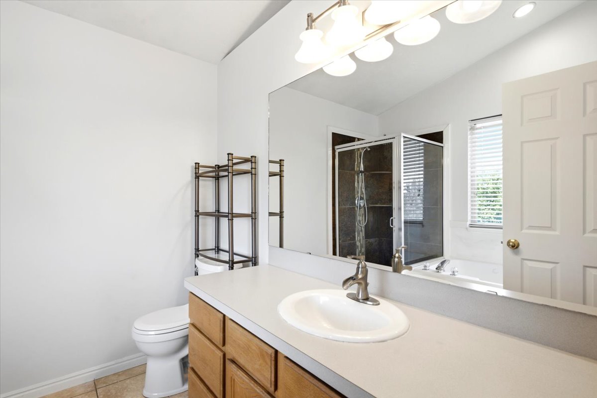 Bathroom featuring a vanity with a light-colored countertop, an undermount sink, and wood-finish cabinetry