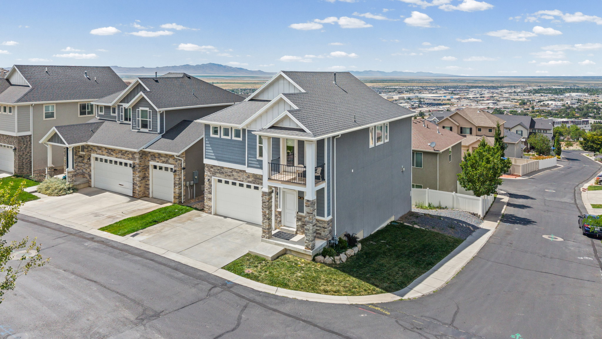 Contemporary two-story residence featuring a light blue and gray exterior with stone accents, a two-car garage, and a second-story balcony