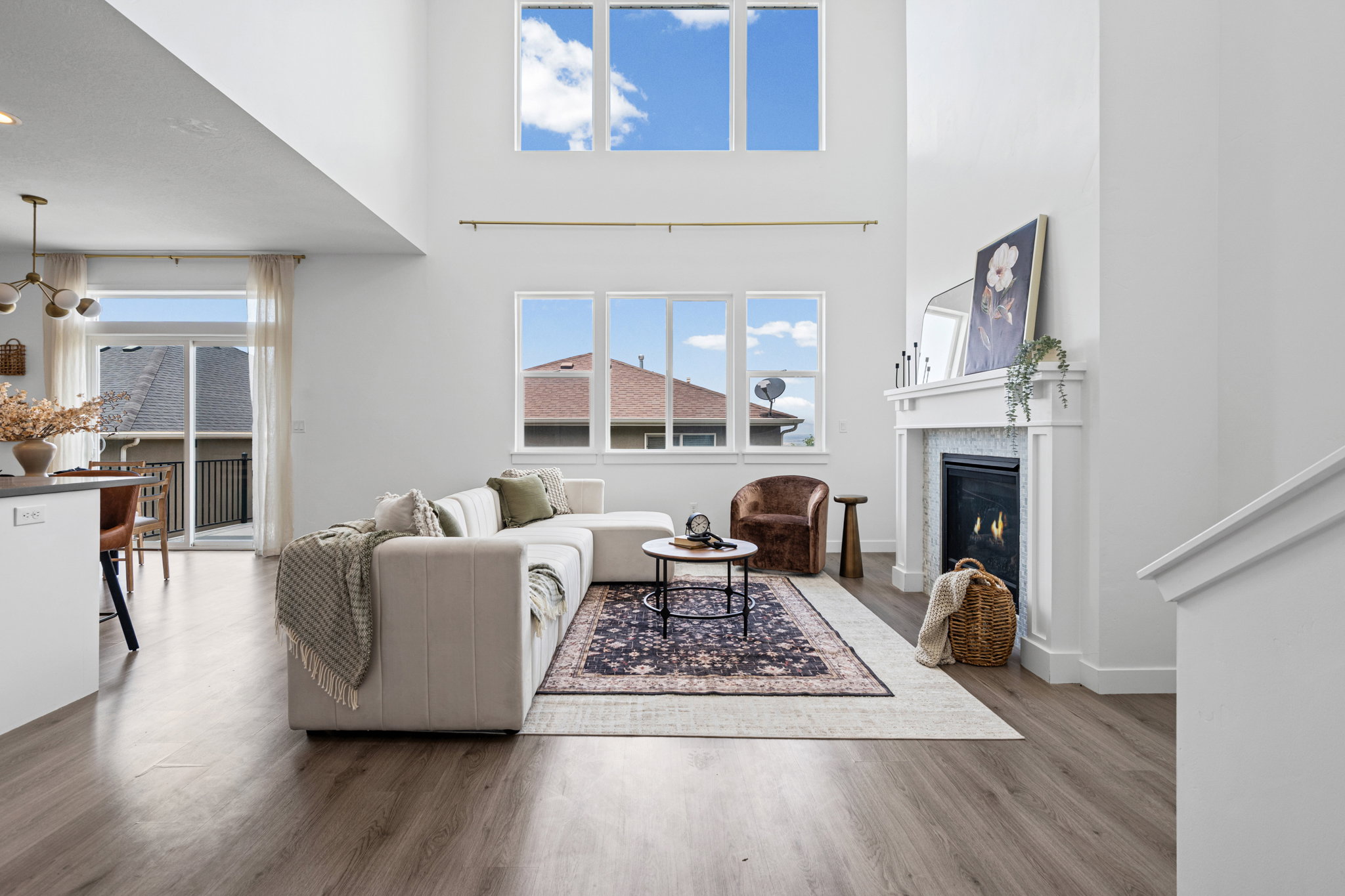 Living area featuring high ceilings with upper windows, a fireplace with a white mantel and tiled surround, and wood-finish flooring