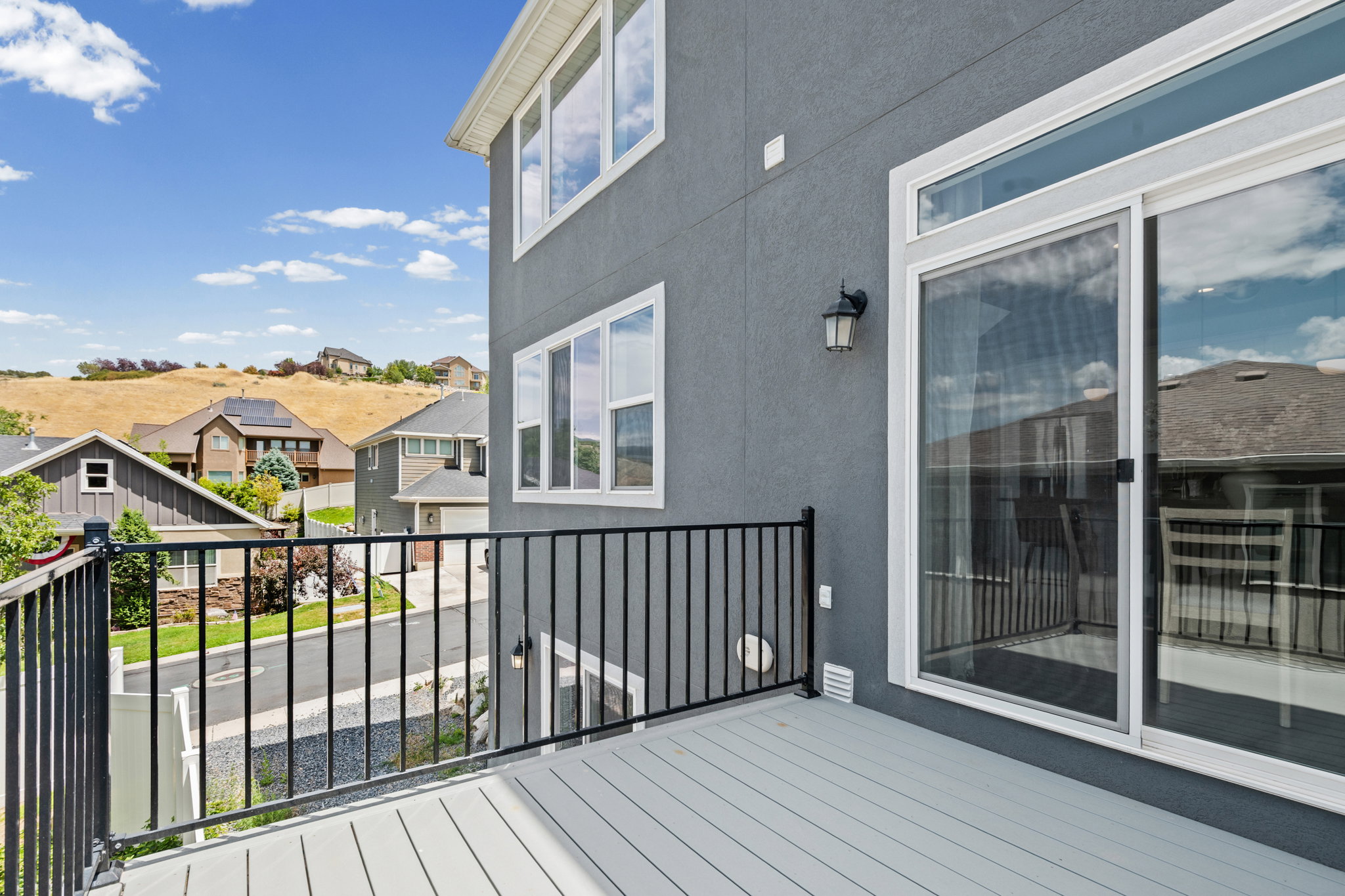 Exterior deck featuring composite decking, black metal railing, and a sliding glass door