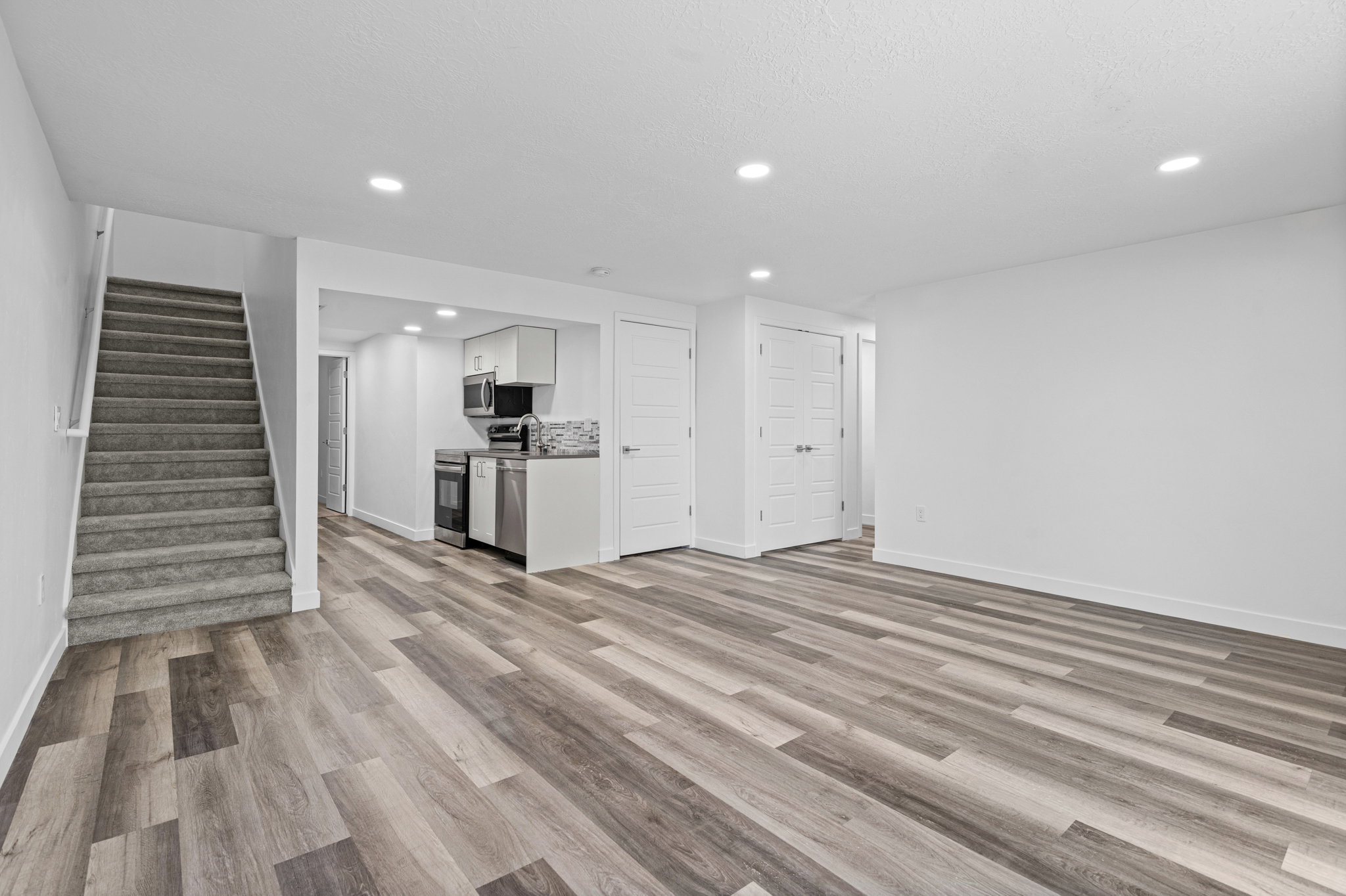 Spacious living area featuring wood-finish flooring, recessed lighting, and a neutral color palette