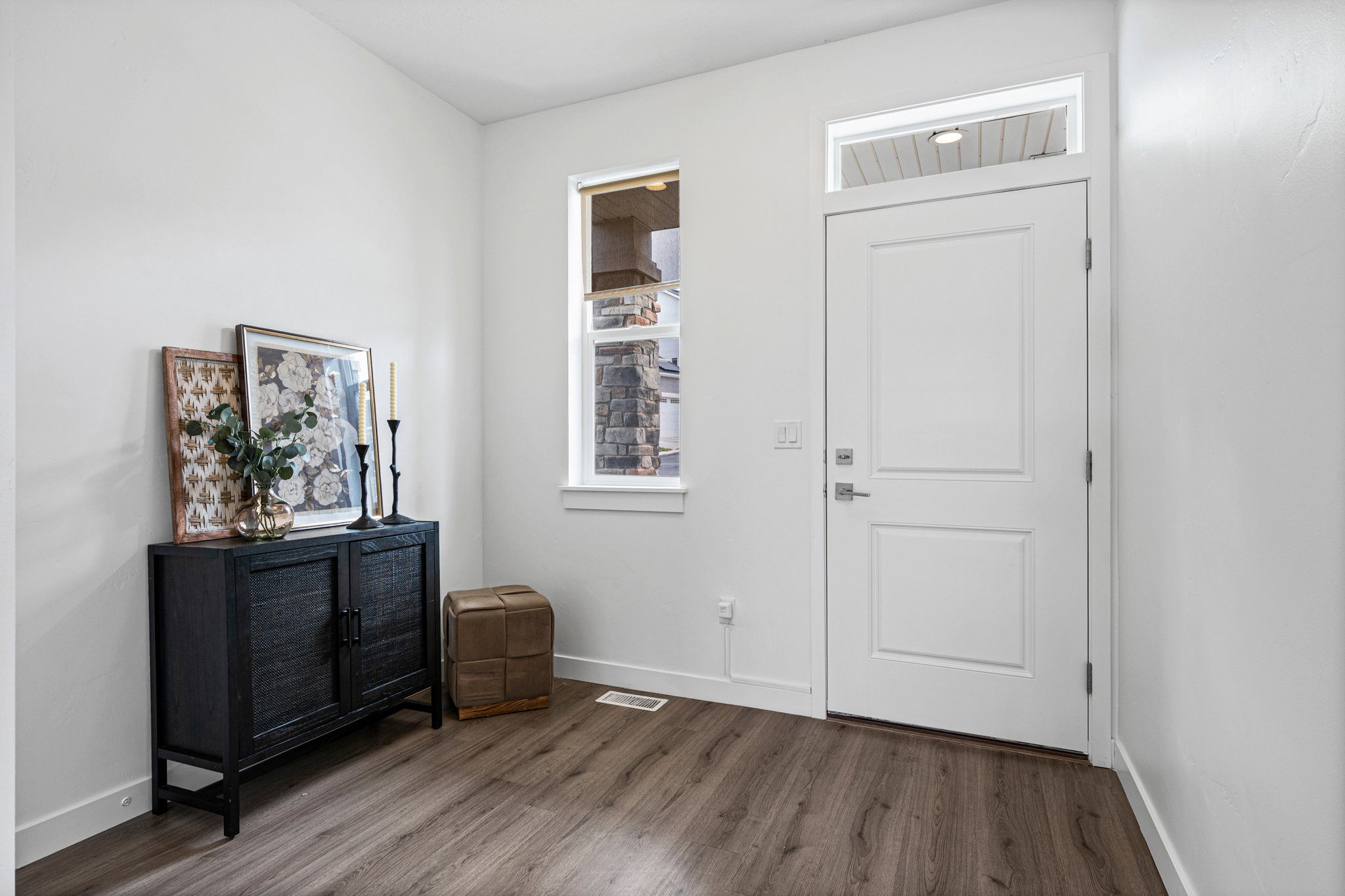 Entryway featuring a white paneled door with a transom window, wood-finish flooring, and white baseboards