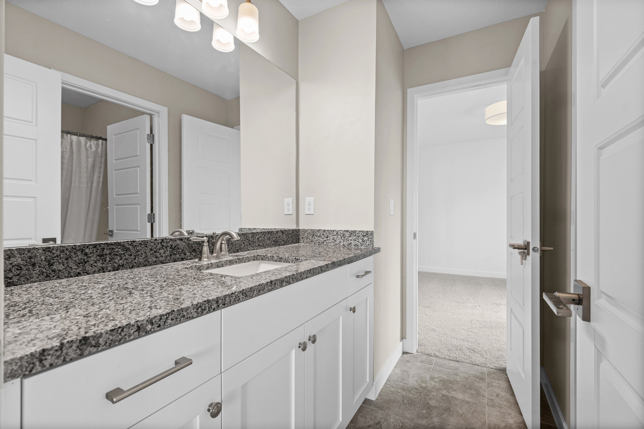 Spacious bathroom featuring a double vanity with granite countertops, undermount sinks, and contemporary brushed nickel hardware