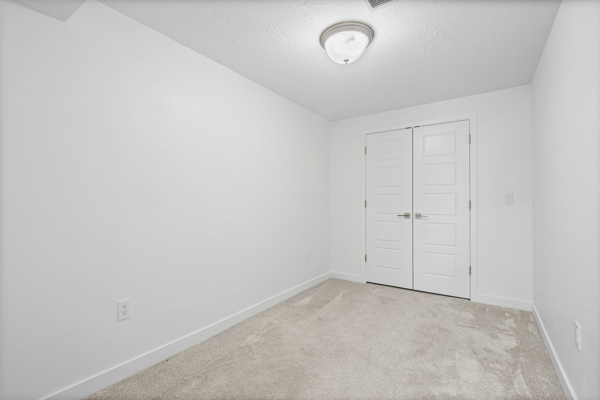 Light gray carpeted room featuring white walls and a white ceiling