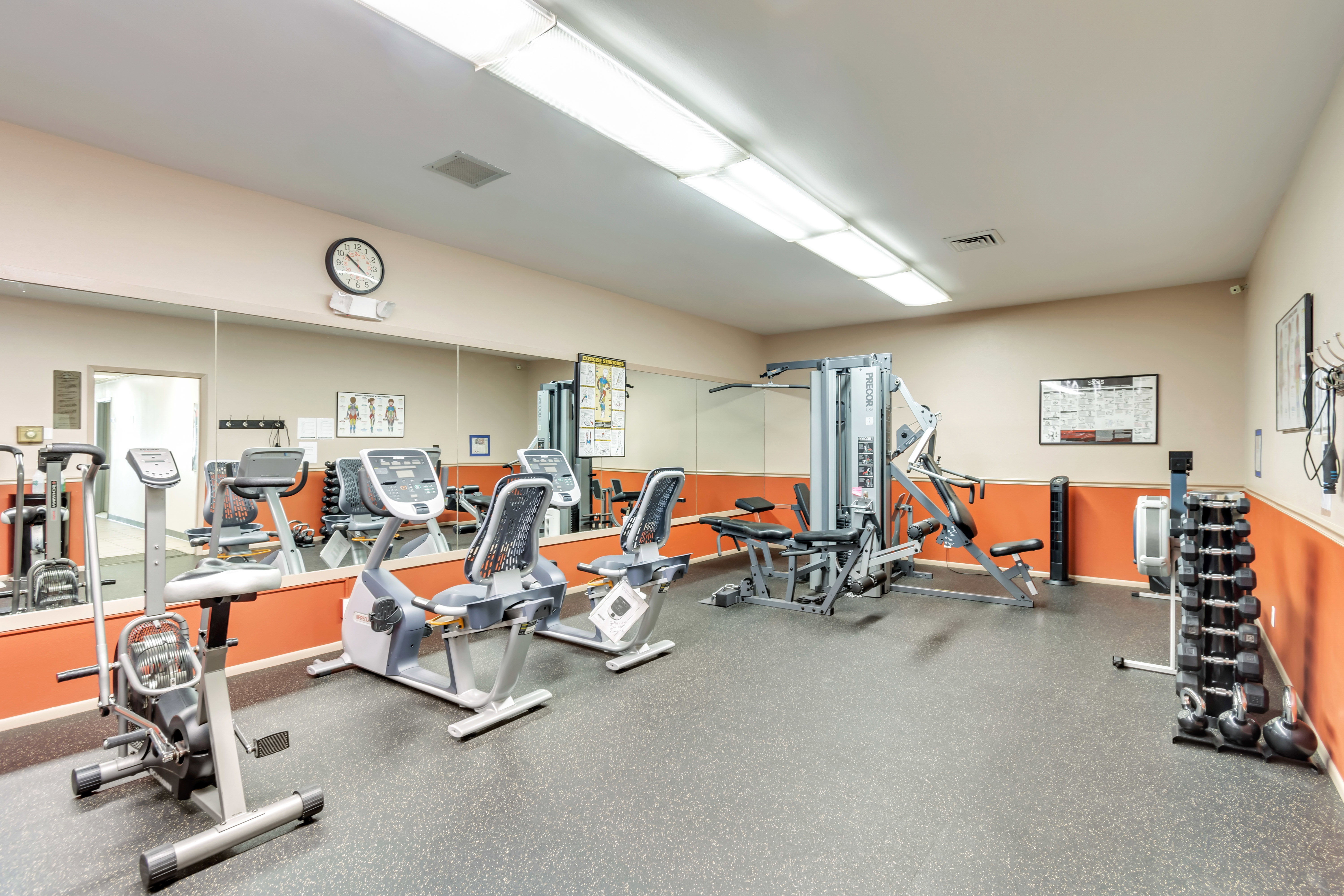 Fitness center featuring rubber flooring, mirrored wall, recessed lighting, and a selection of exercise equipment