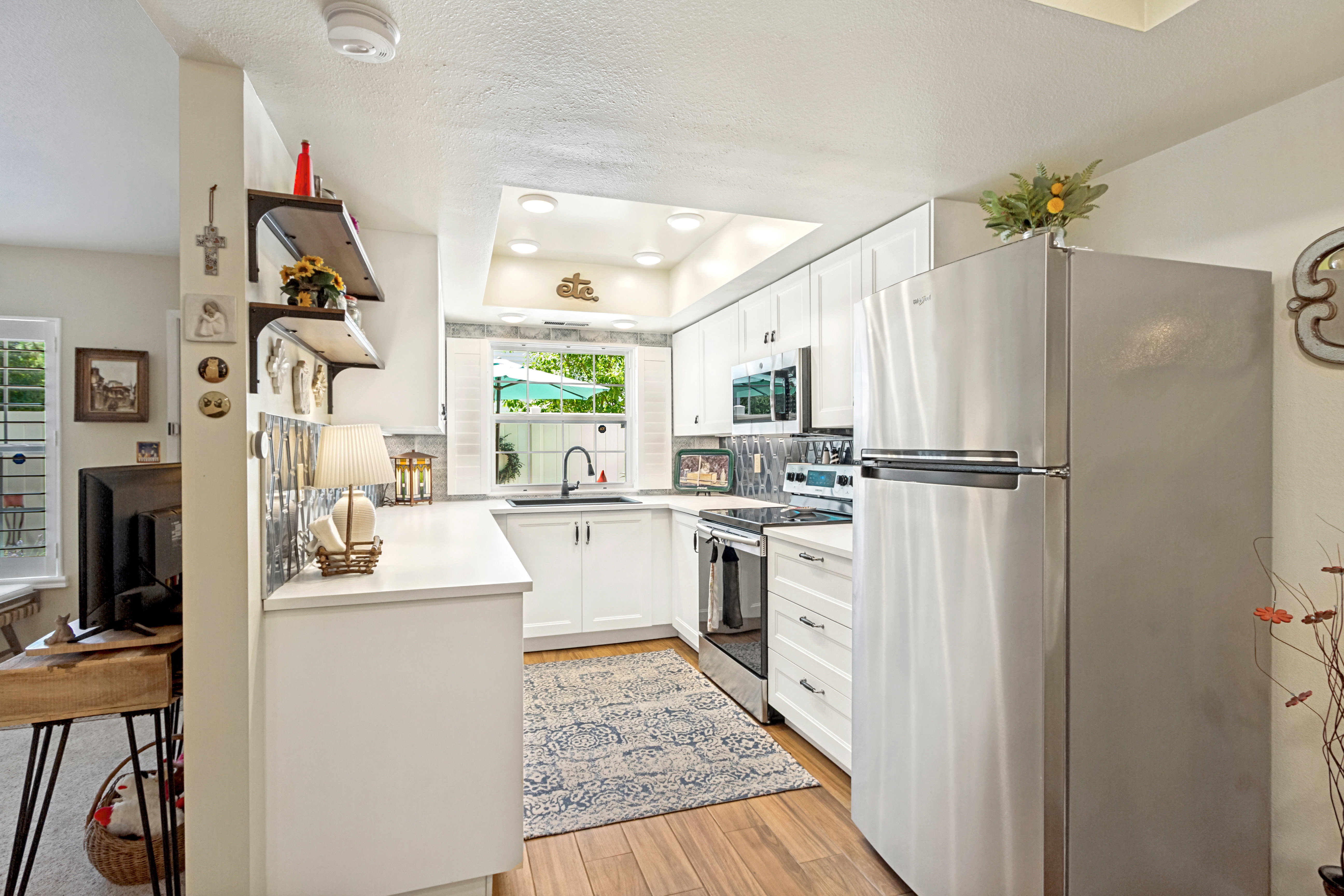 Kitchen featuring wood-finish flooring, white cabinetry, stainless steel appliances, and a tiled backsplash