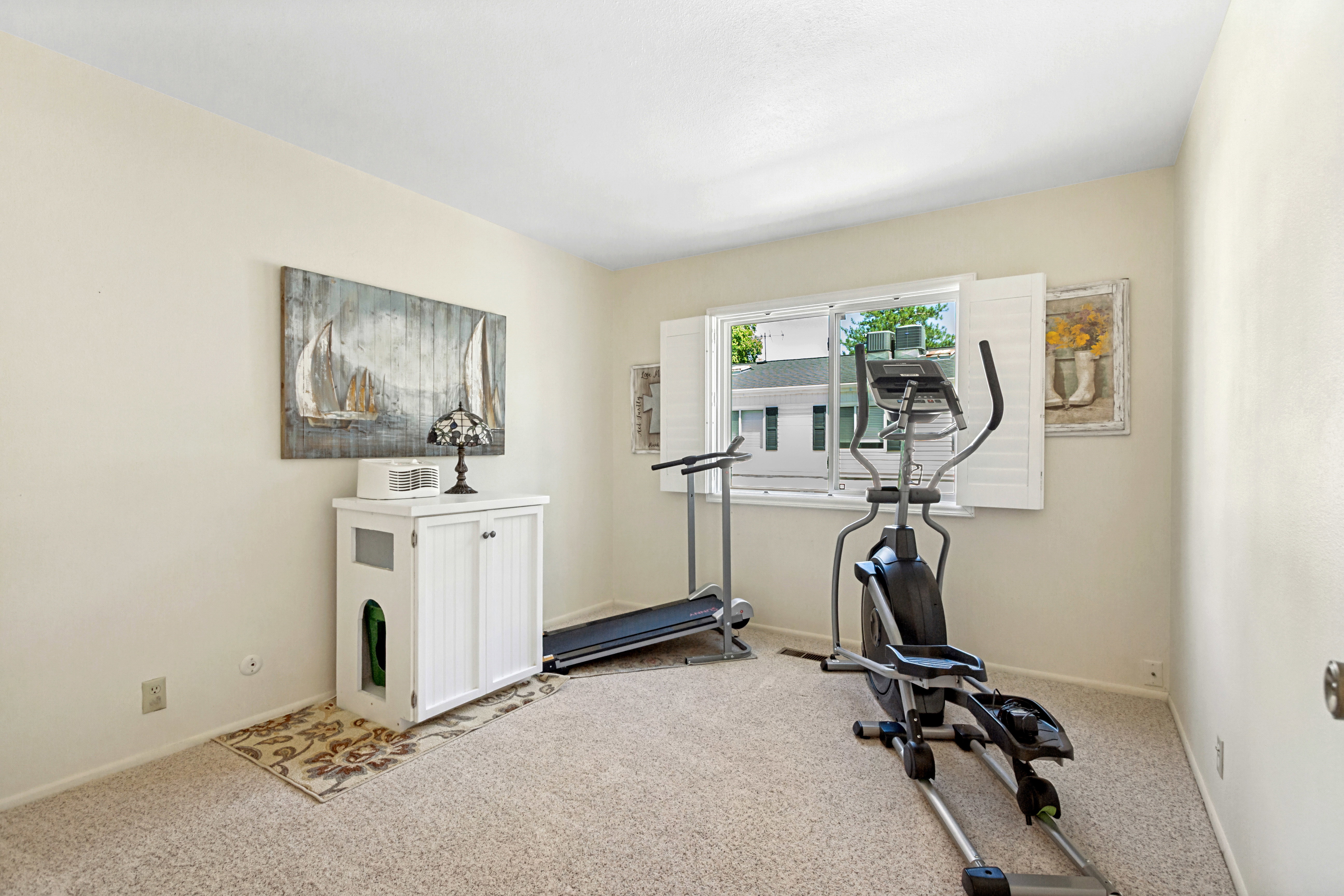 Spacious room featuring neutral carpeting, a dual-pane window with white plantation shutters, and light-colored walls