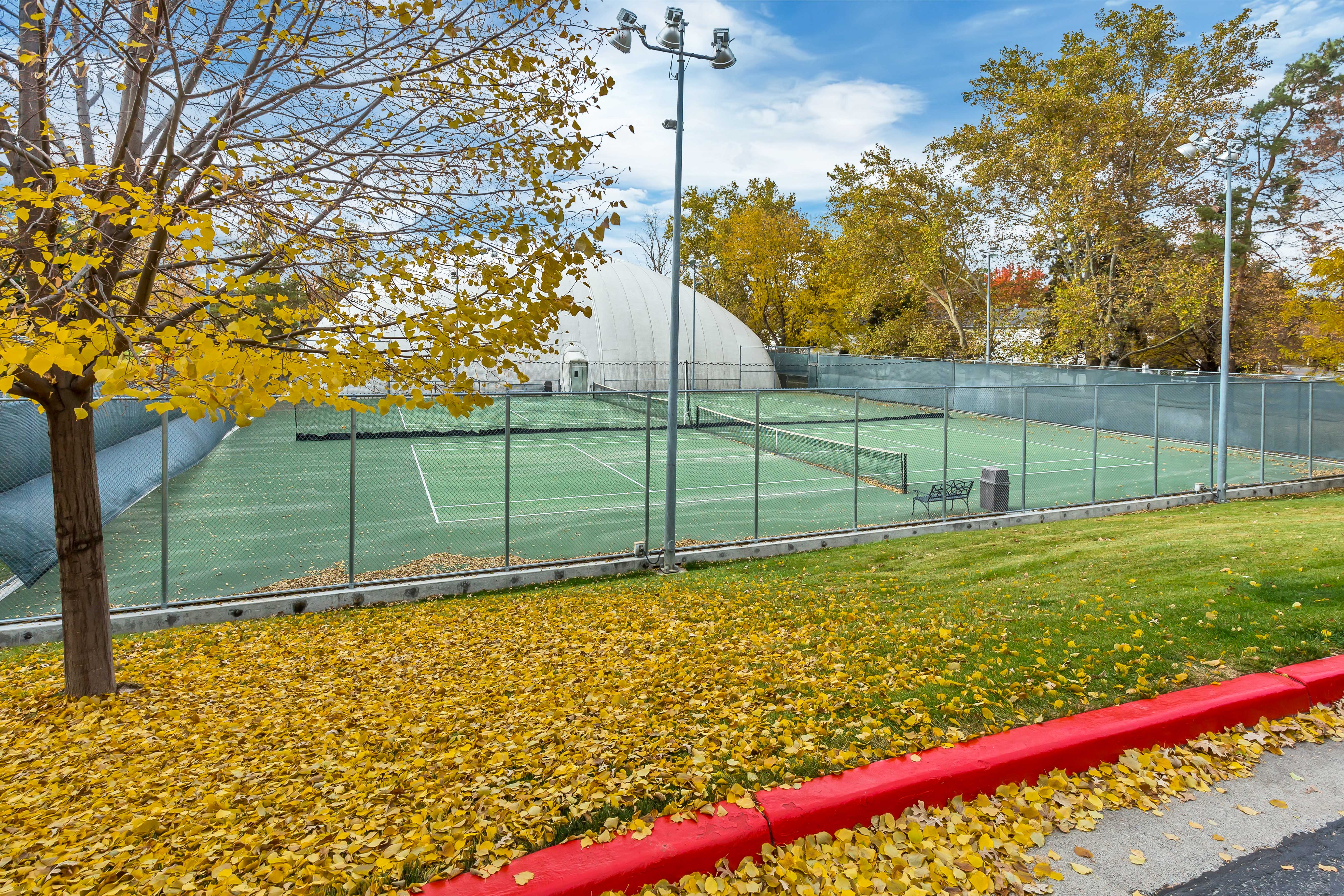 Outdoor tennis courts featuring perimeter fencing and overhead lighting