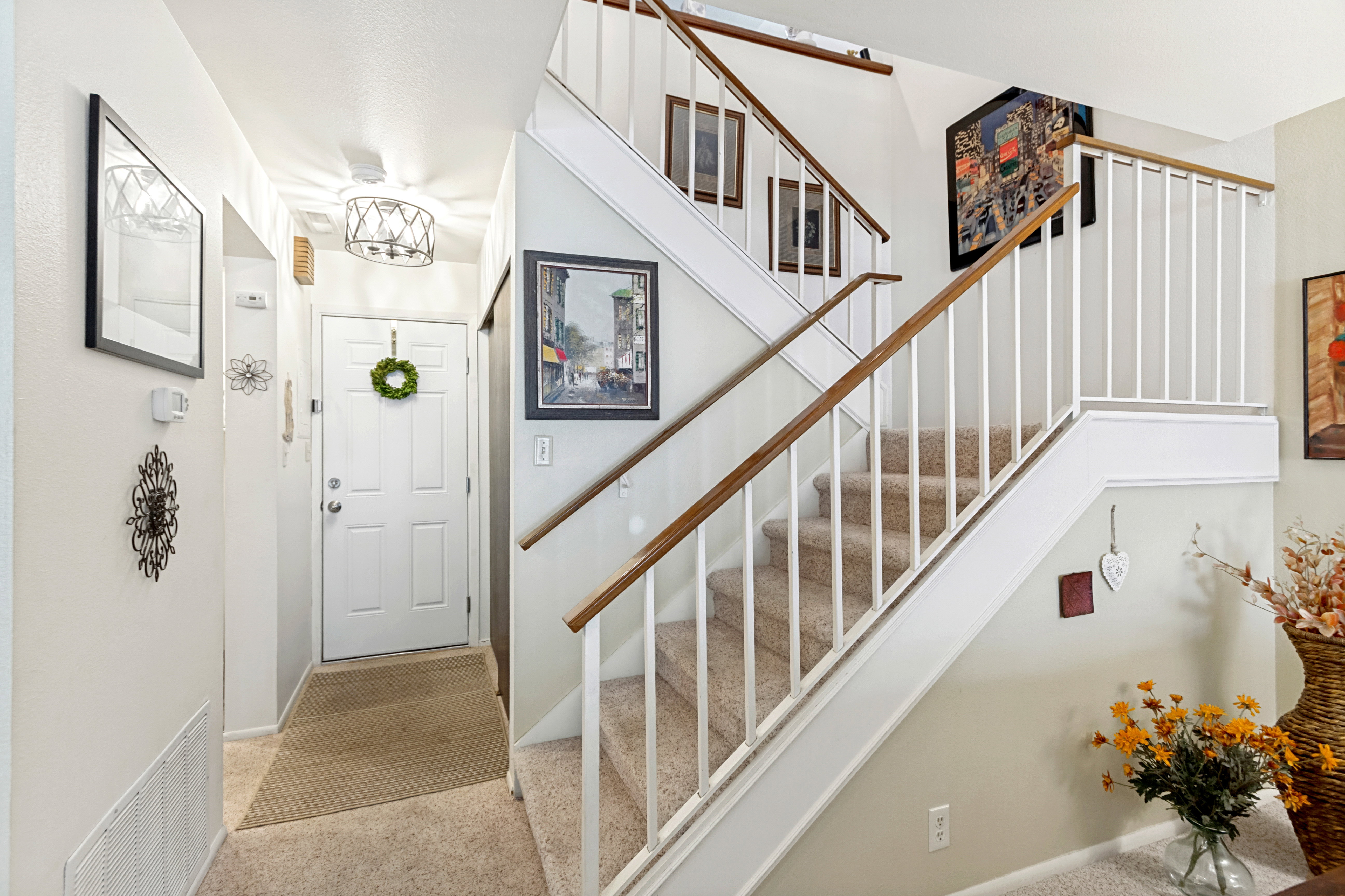 Entryway featuring a staircase with carpeted treads, white balusters, and wood-finish handrails