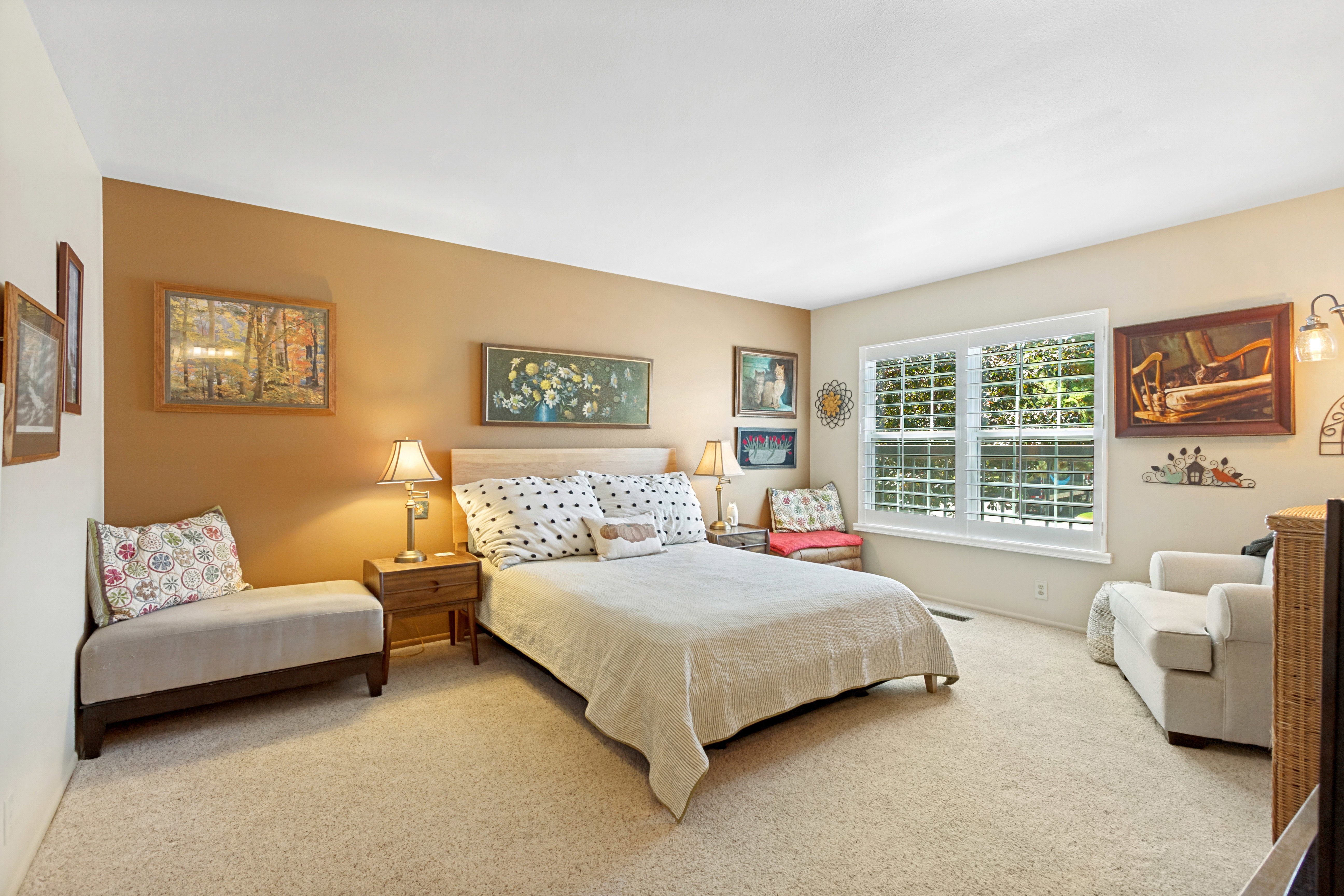 Expansive room featuring a large window with plantation shutters, neutral wall tones, and carpet flooring