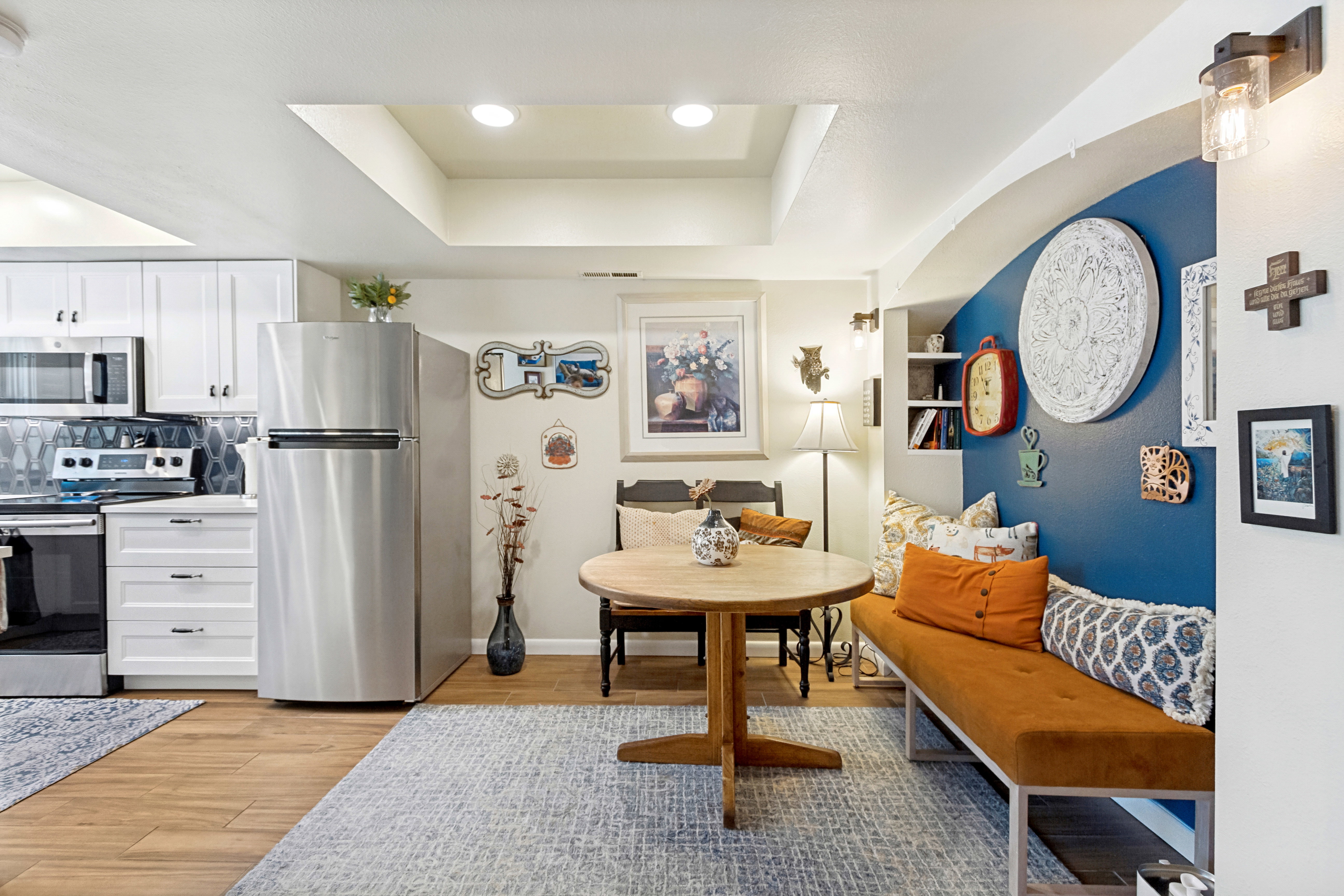 Open-concept living space featuring wood-finish flooring, recessed lighting, white cabinetry, stainless steel appliances, and a built-in bench