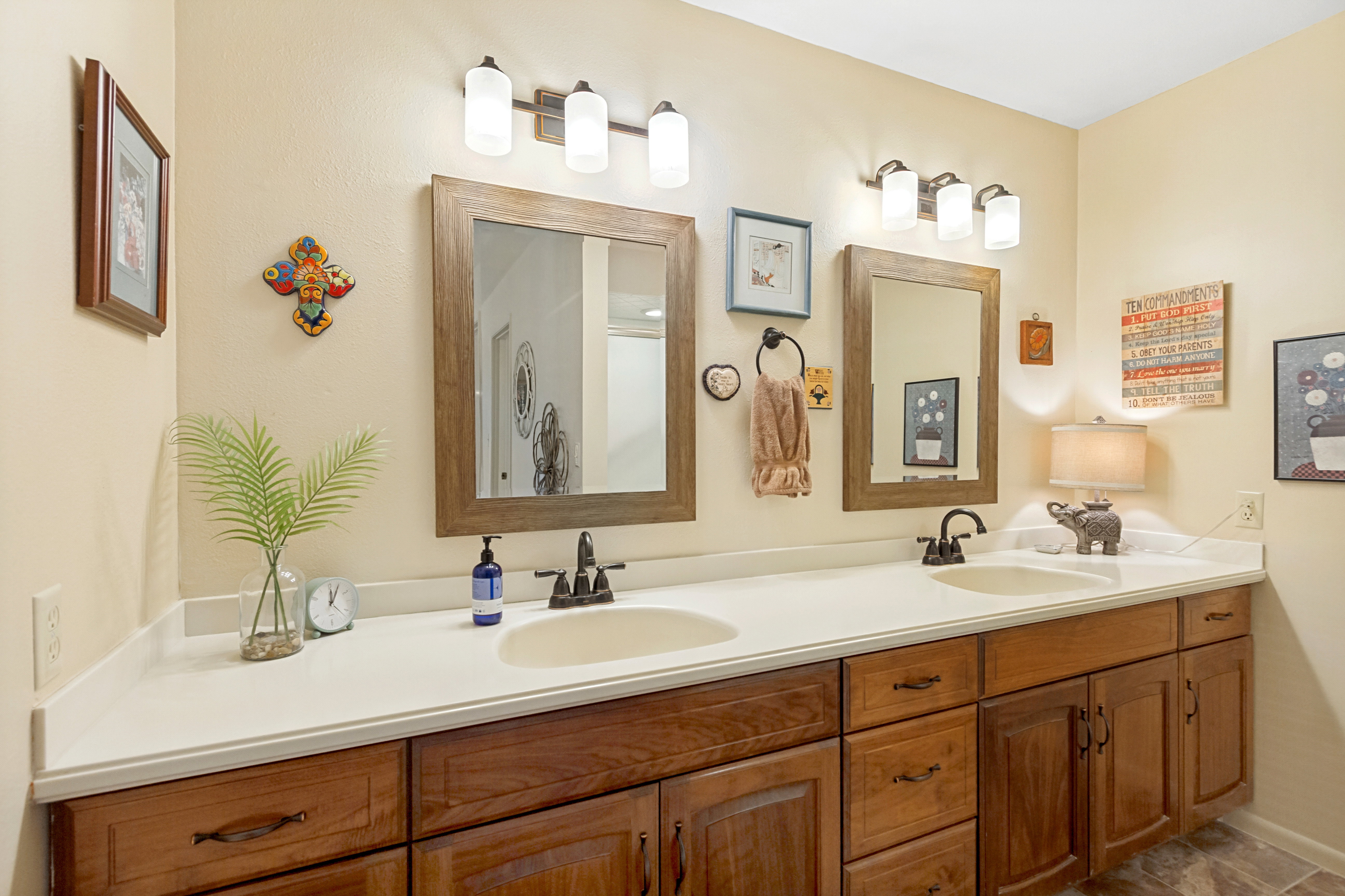 Double vanity featuring wood-finish cabinetry, integrated sinks, and light-toned countertops