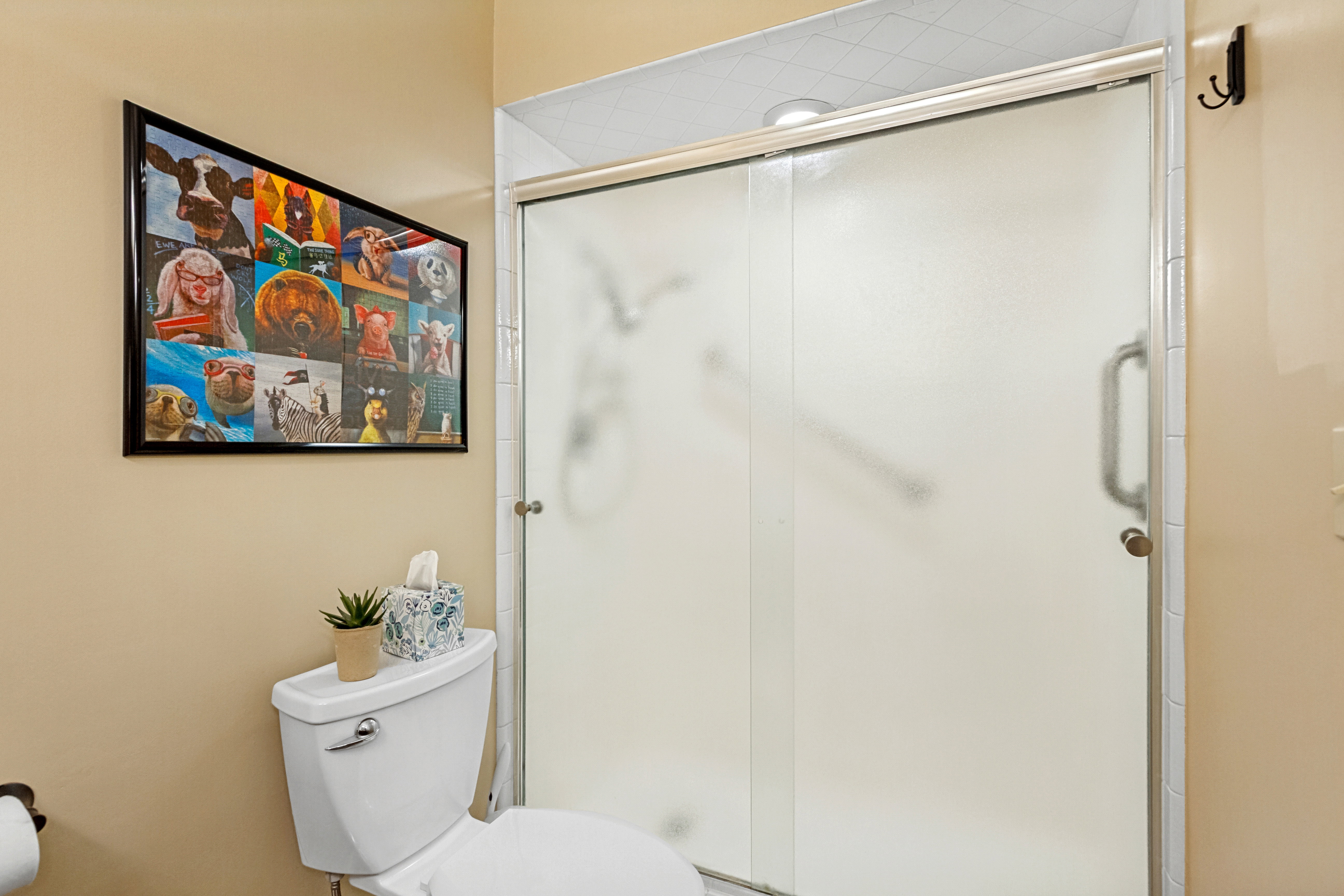 Frosted glass shower enclosure with sliding door, featuring a curved grab bar and brushed nickel hardware