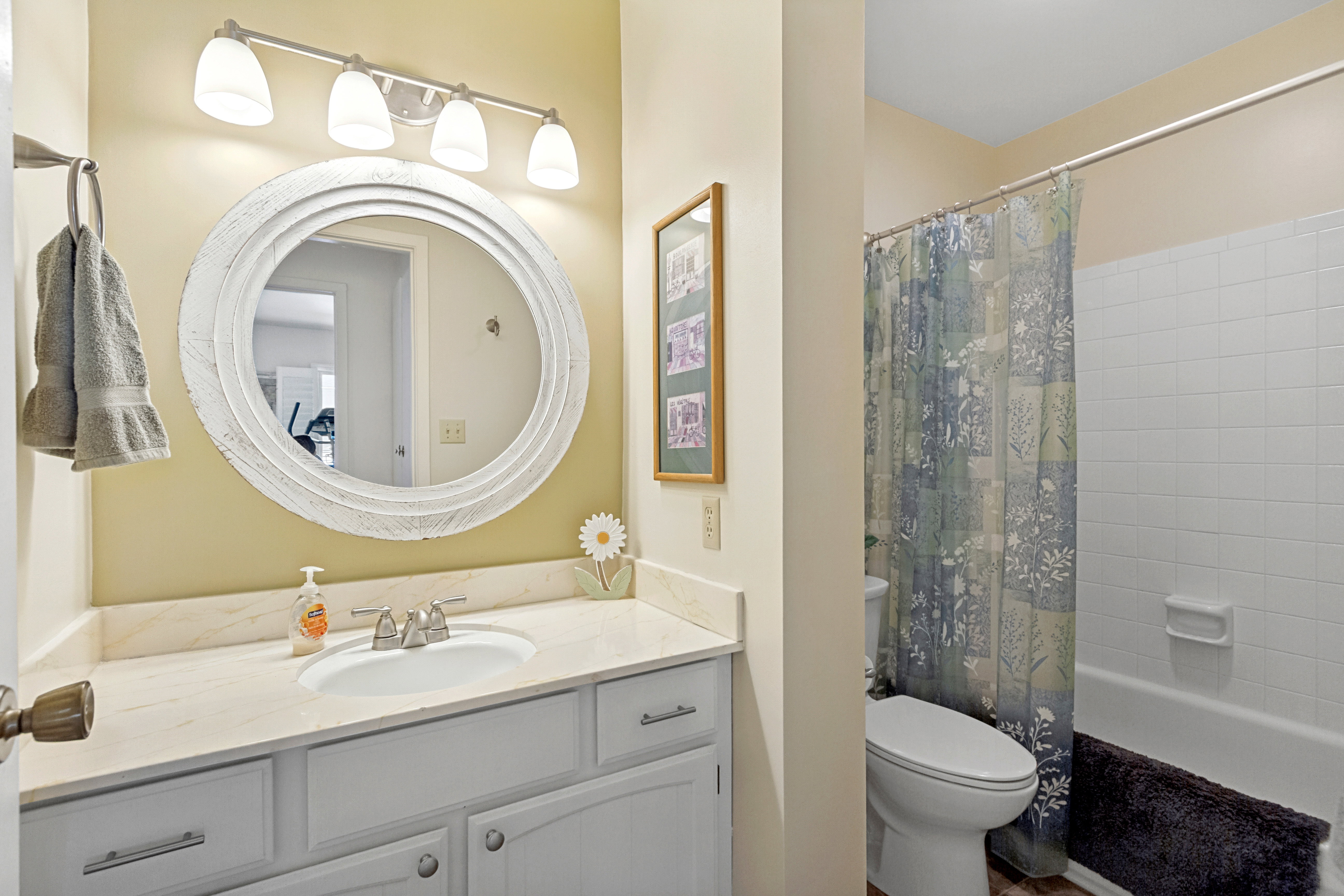 Bathroom featuring a vanity with a light-colored countertop, an oval undermount sink, and a four-light fixture
