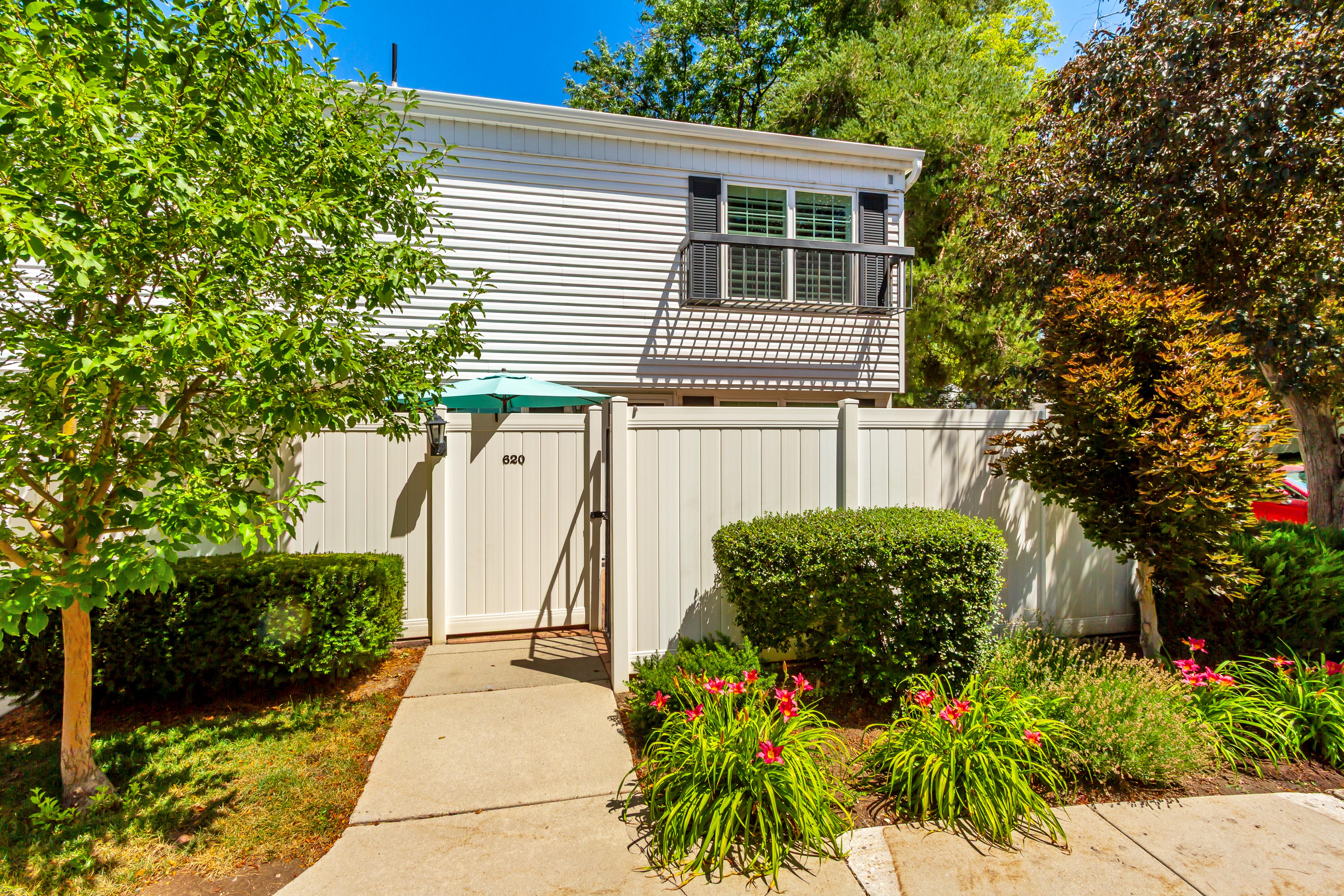 Exterior featuring white siding, a private balcony with black railing, and a white privacy fence