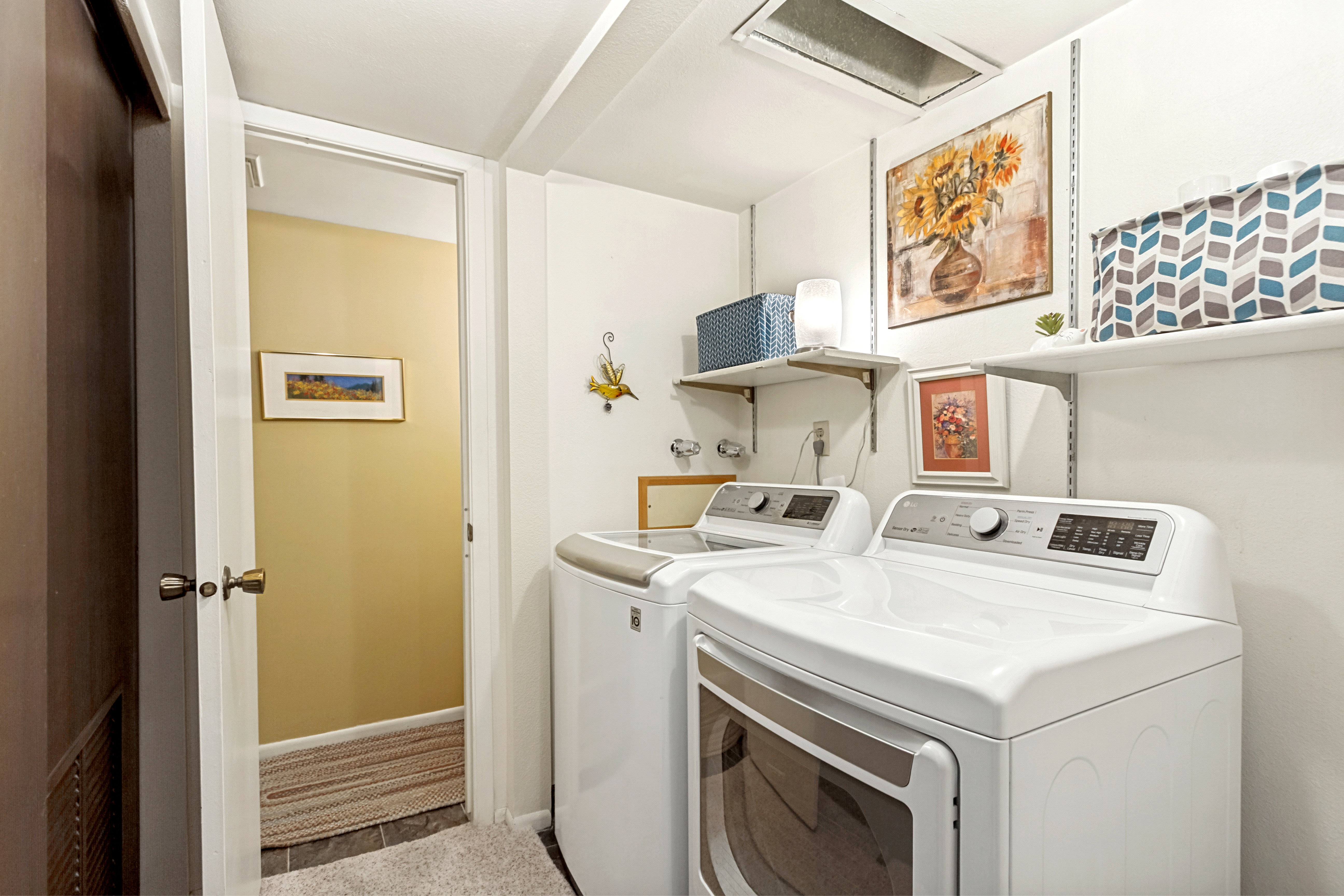 Dedicated laundry area featuring a washer and dryer, open shelving for storage, and overhead lighting