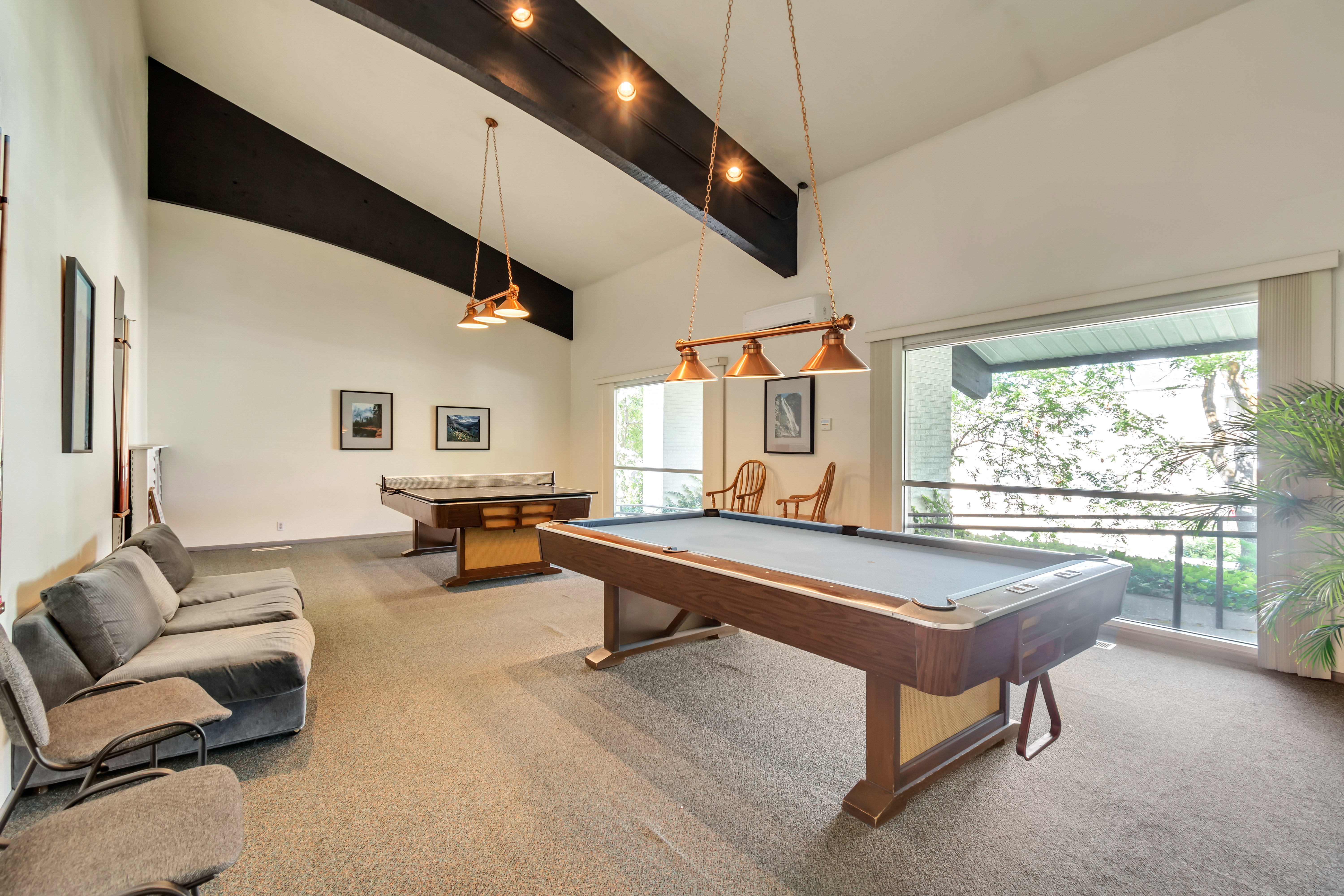 Spacious entertainment room featuring vaulted ceilings with exposed dark beams and recessed lighting