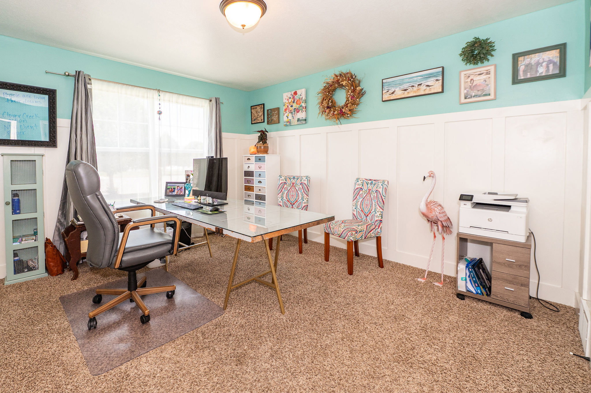 Spacious room featuring board and batten wainscoting, light turquoise walls, and a large window with sheer and blackout curtains