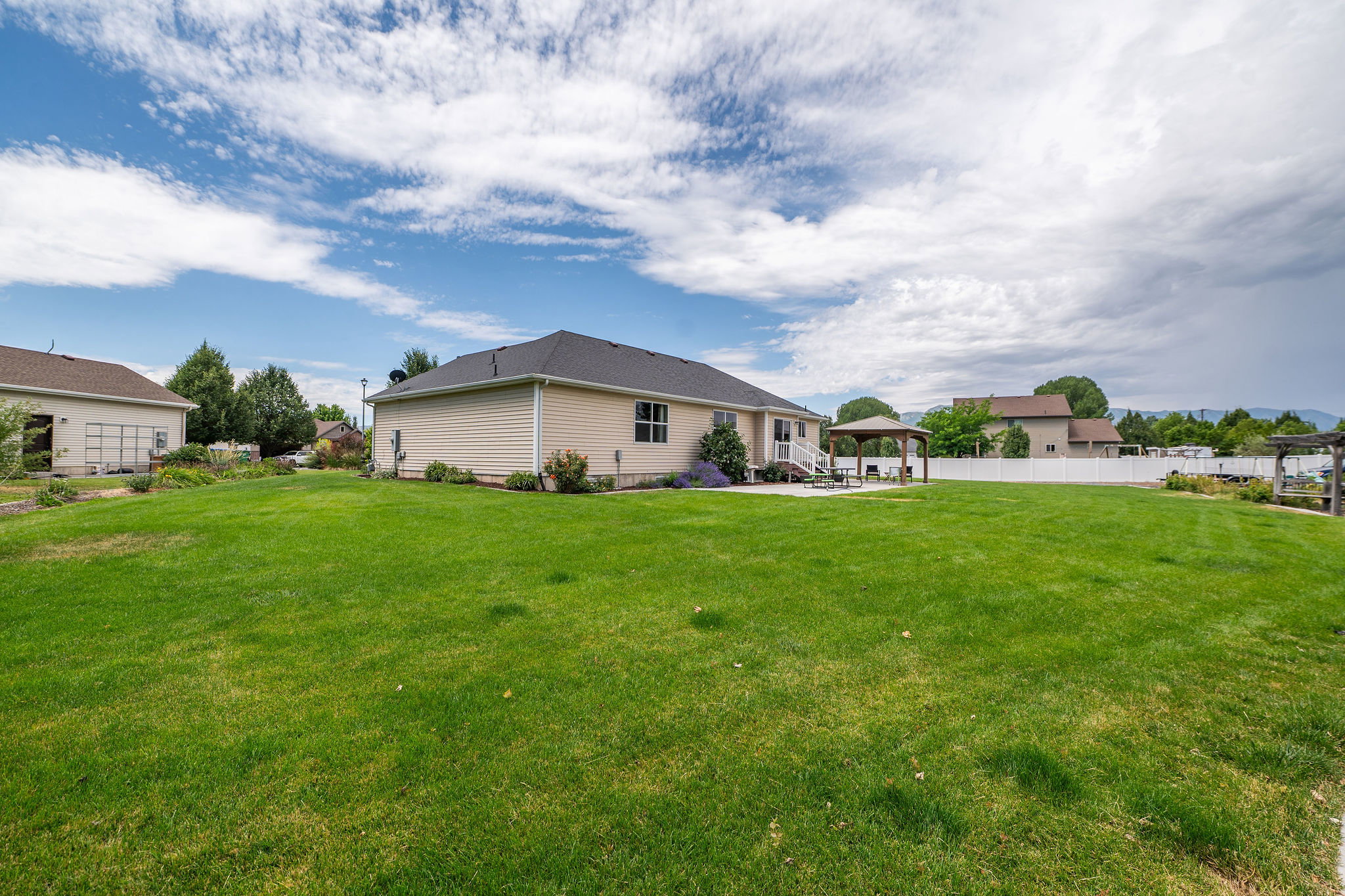Expansive rear yard featuring a large lawn area, a back patio, and a dedicated pergola structure