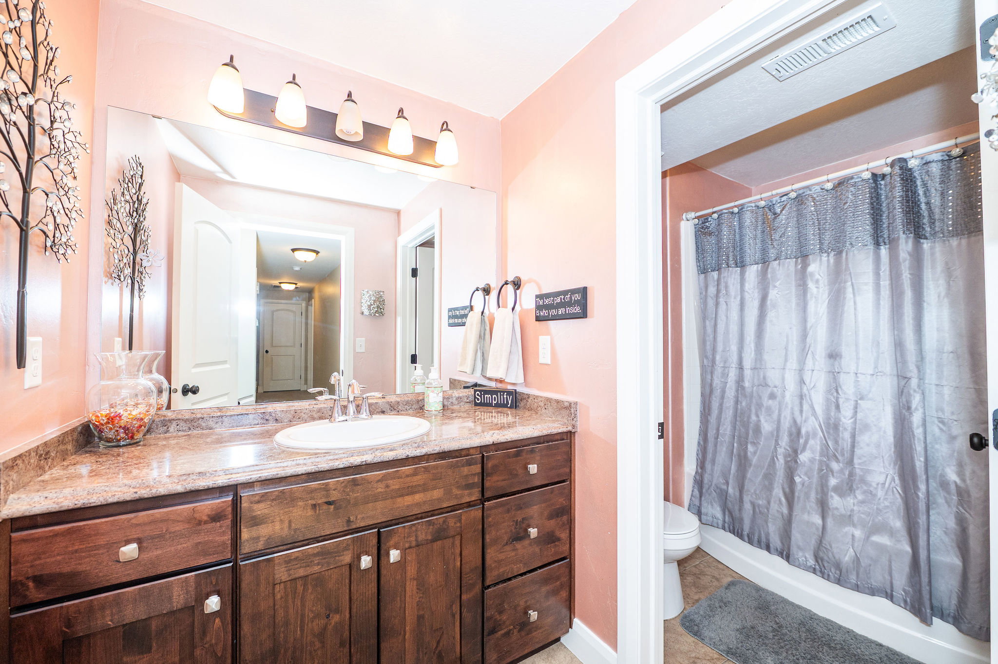Bathroom featuring a dark wood-finish vanity with an integrated sink, a large mirror, and a five-light fixture