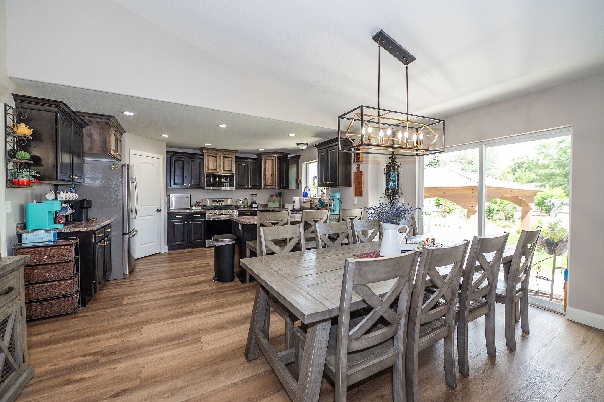 Open-concept kitchen and dining area featuring wood-finish flooring, recessed lighting, and a modern rectangular chandelier