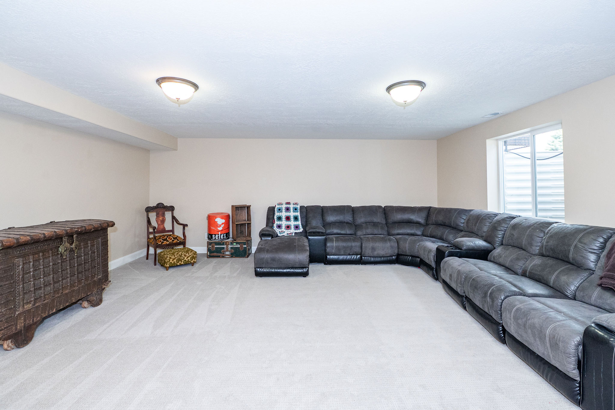 Spacious room featuring neutral carpeting, light-toned walls, and a recessed window with a window well