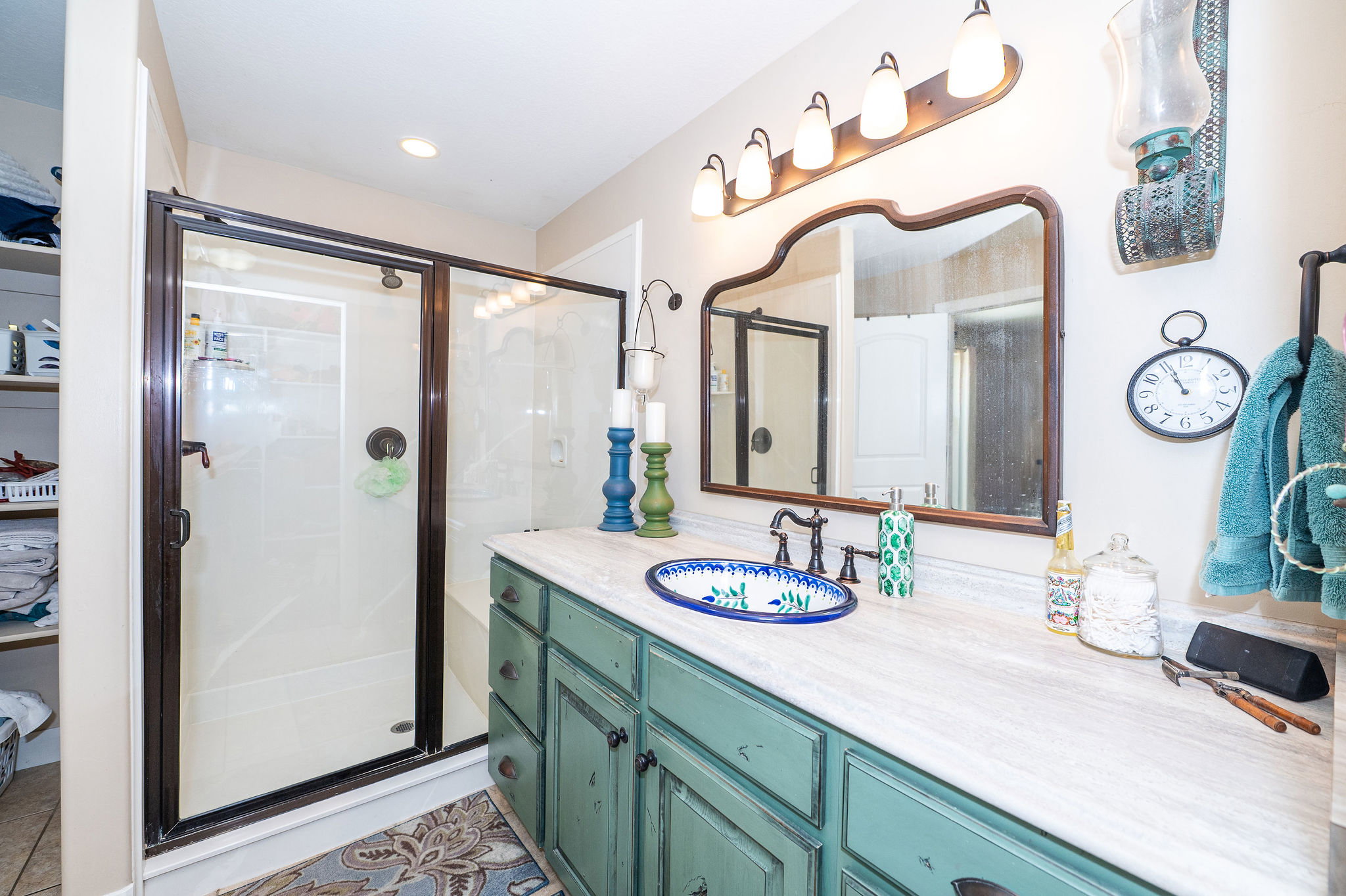 Bathroom featuring an expansive vanity with a light-toned countertop, a decorative basin sink, and a framed mirror