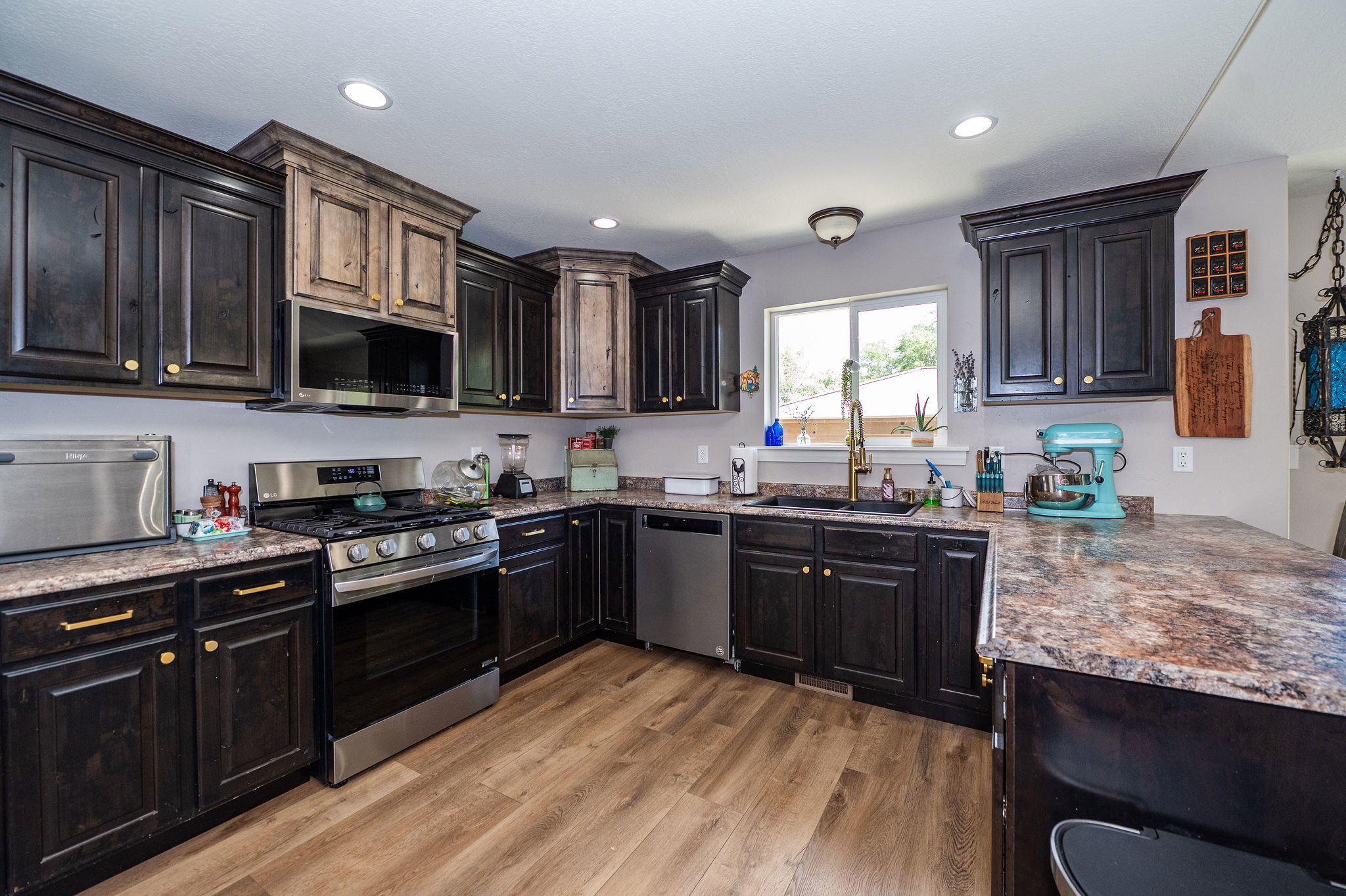 Kitchen featuring dark wood cabinetry with gold-tone hardware, wood-finish flooring, and speckled countertops