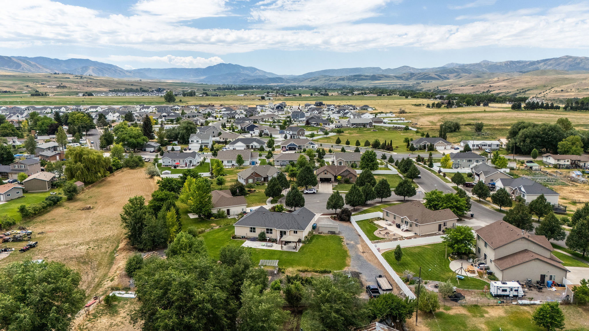 Residential neighborhood featuring single-family homes, mature landscaping, paved streets, and mountainous terrain in the distance
