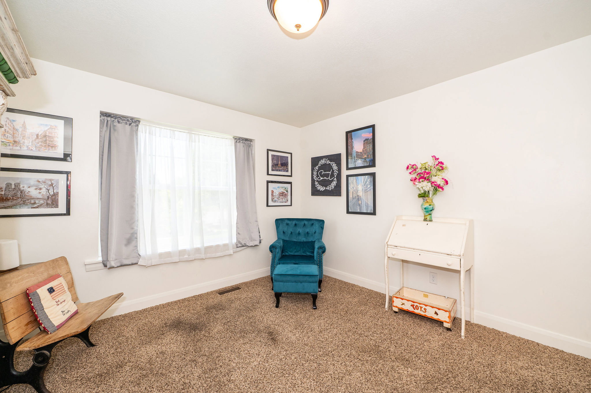 Carpeted room featuring a ceiling-mounted light fixture, white walls, and a window with sheer and blackout curtains