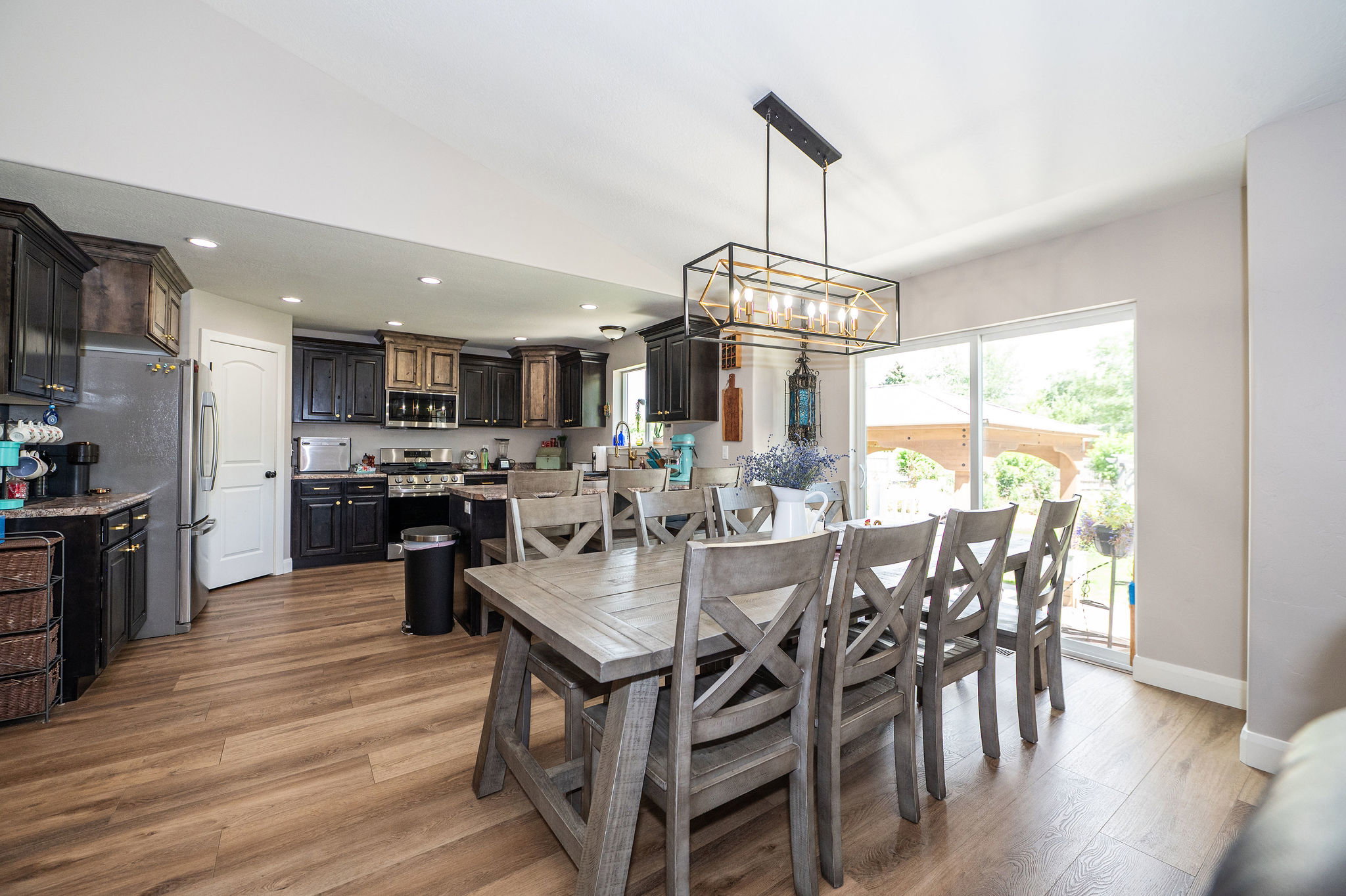 Open-concept kitchen and dining area featuring wood-finish flooring, recessed lighting, and a modern rectangular chandelier