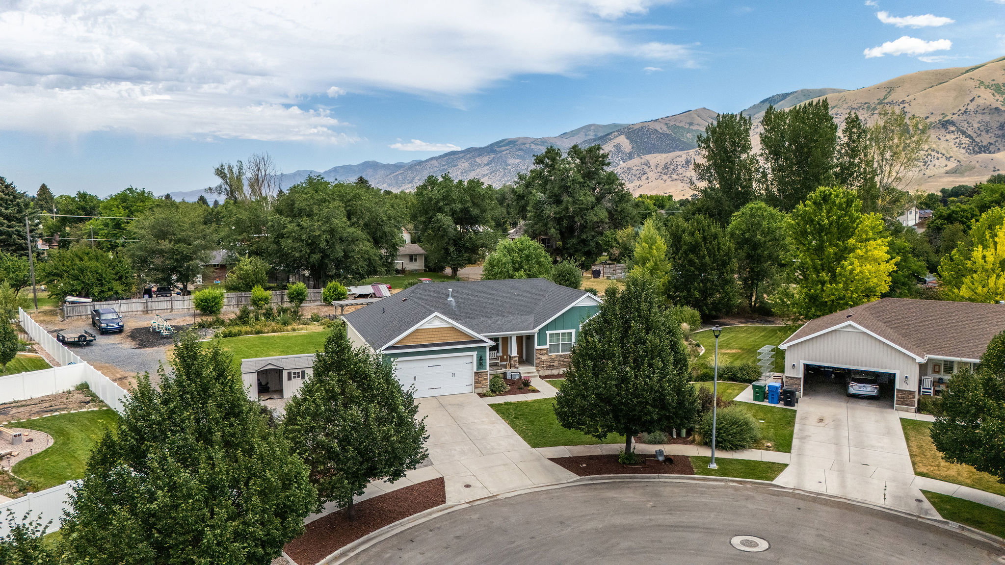 Ranch-style home featuring a two-car garage, an asphalt shingle roof, and a stone facade accent
